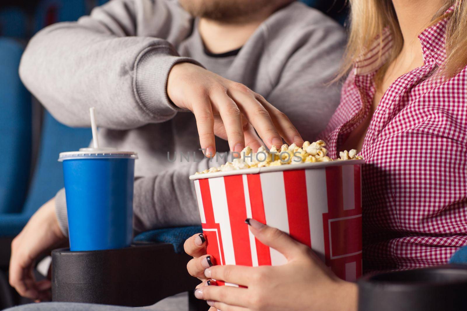 Would you mind? Cropped closeup of a couple watching movies man grabbing popcorn from a popcorn bucket