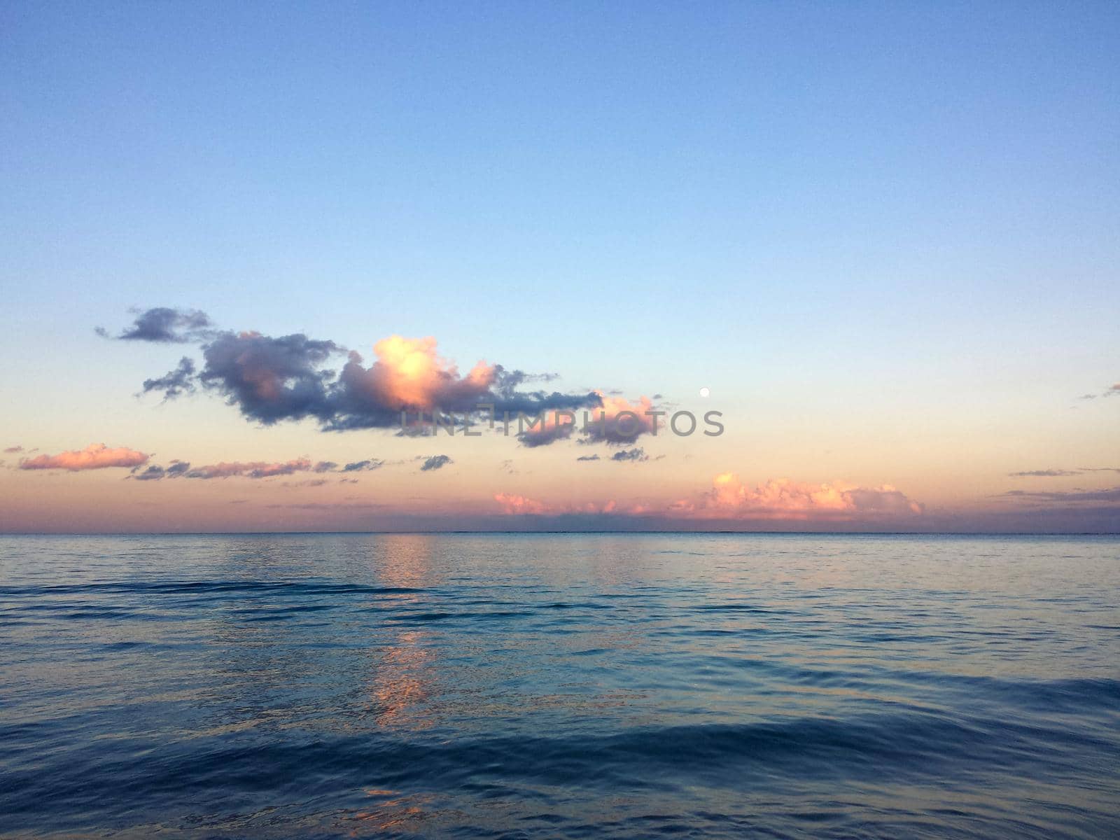 Calm ocean waters of Waimanalo Bay at dusk with clouds and full moon by EricGBVD