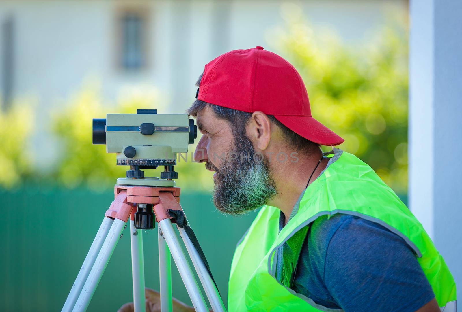 A man works with an optical level to level the landscape