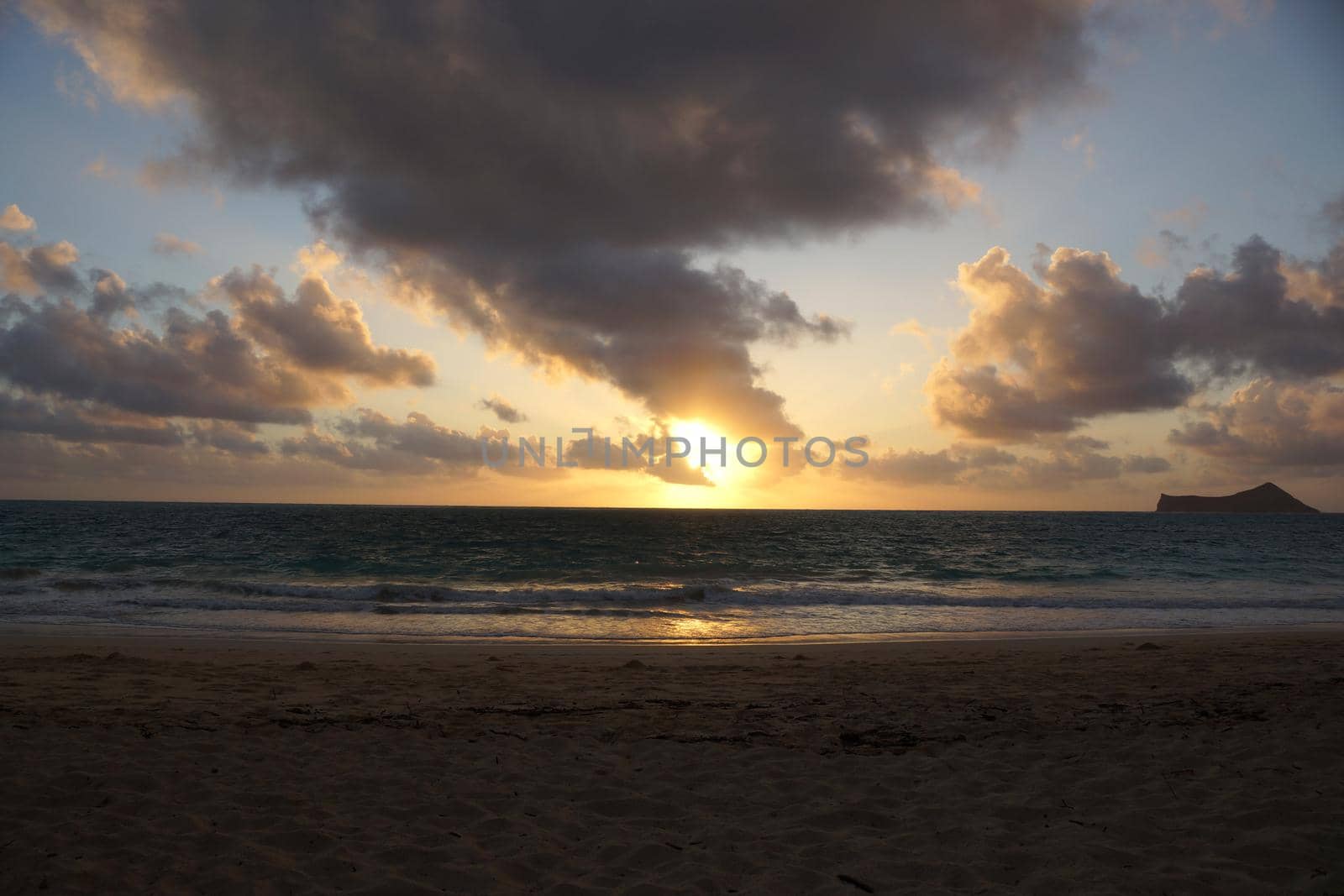 Early Morning Sunrise on Waimanalo Beach over ocean bursting through the clouds on Oahu, Hawai