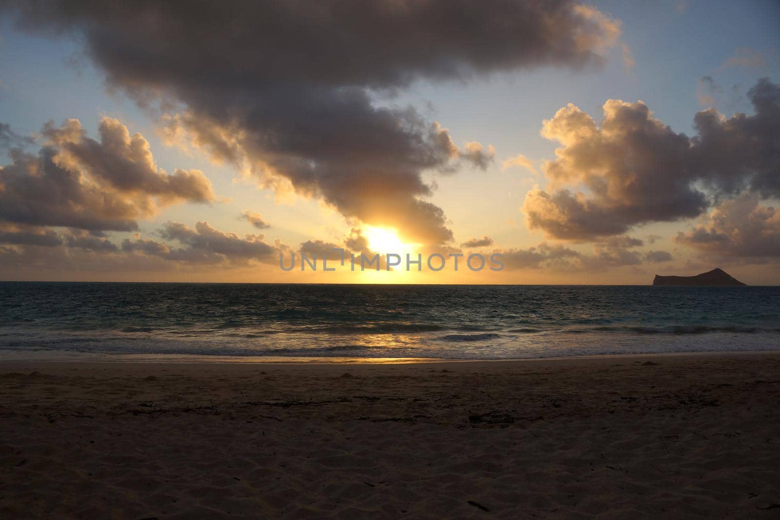 Early Morning Sunrise on Waimanalo Beach on Oahu, Hawaii over ocean bursting through the clouds.