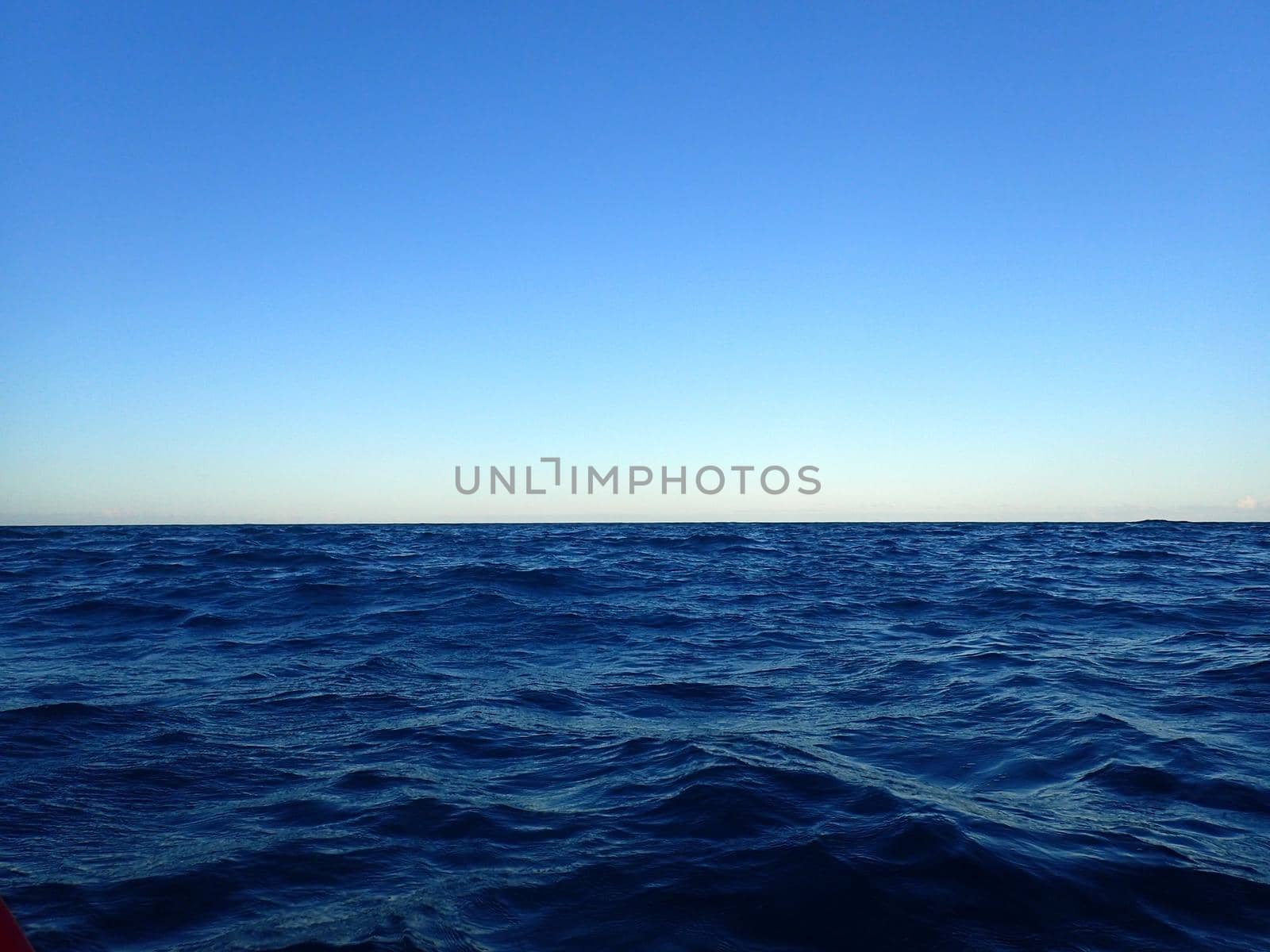 Shallow wavy ocean waters of Waimanalo bay looking into the pacific ocean with a clear blue sky on Oahu.