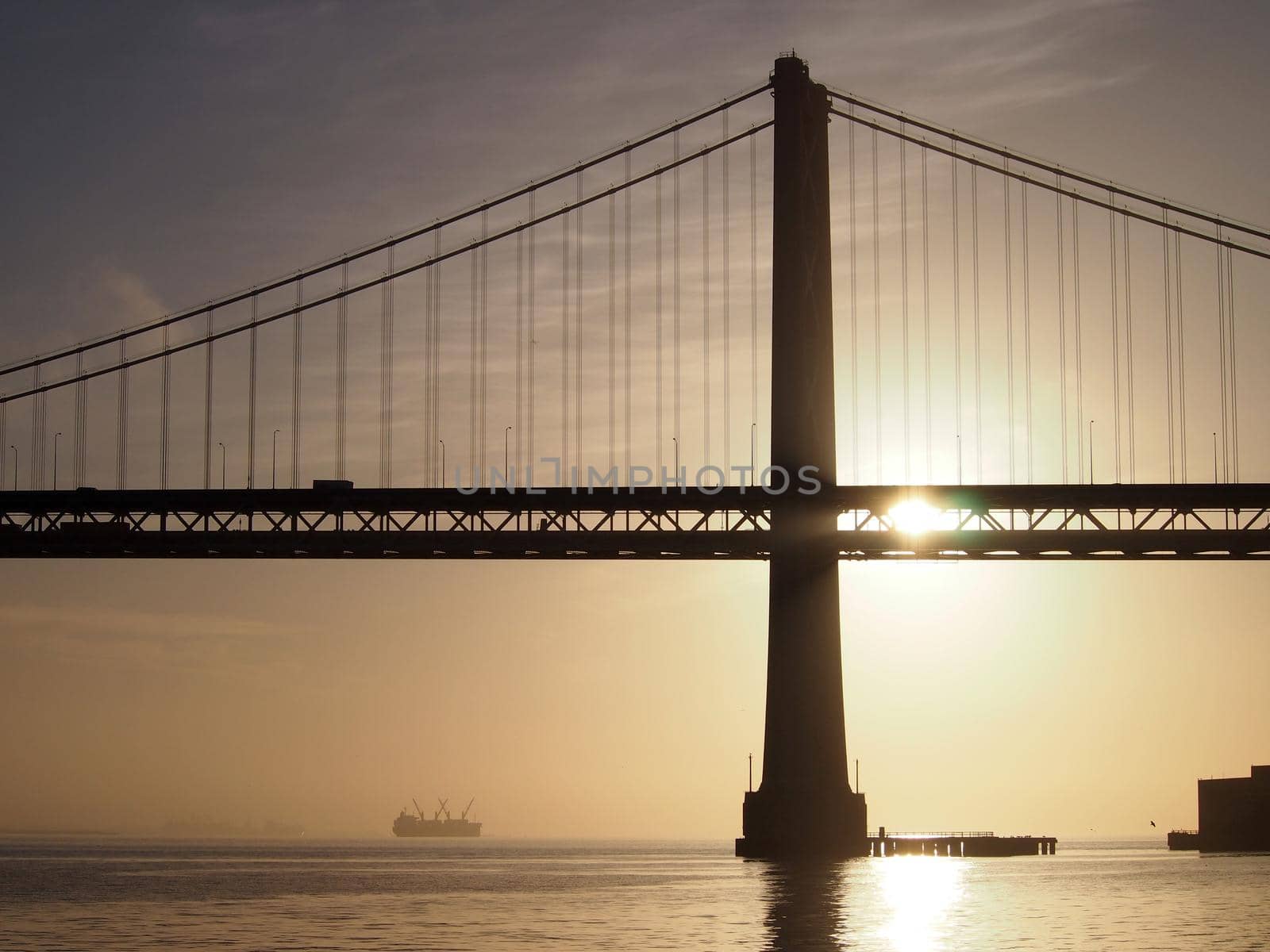 Sunrise over San Francisco Bay and through the Bay Bridge with boats in the water  by EricGBVD