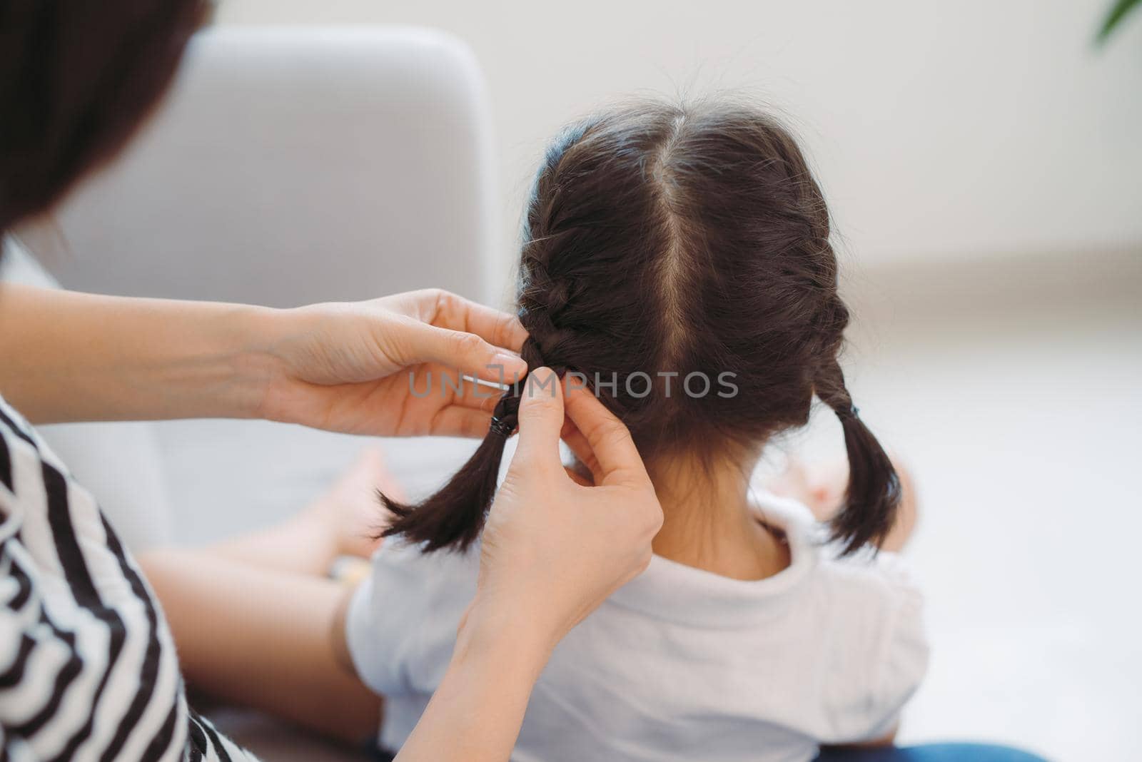 Young loving mother brushing kid daughters hair sitting on sofa, by makidotvn