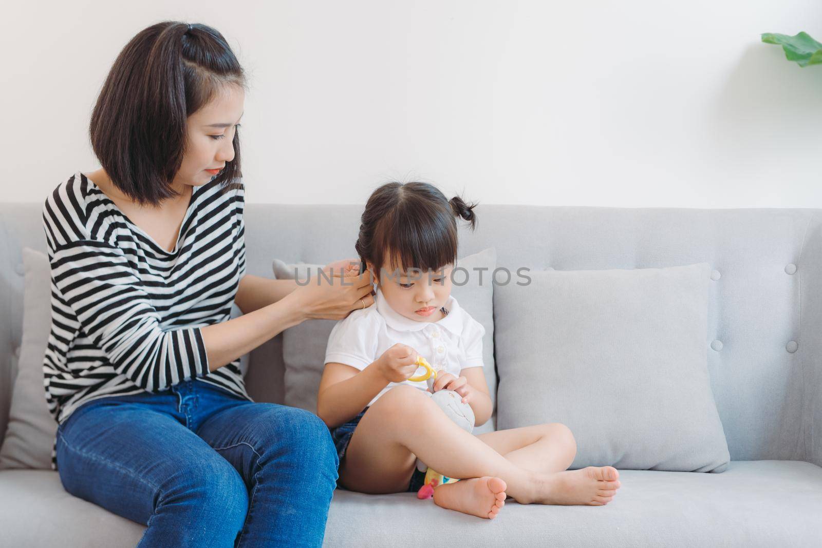 Mother combing daughter, care about hairstyle.