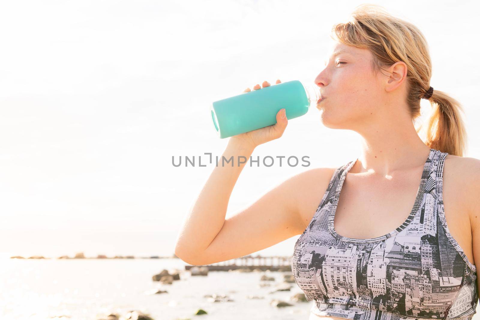 portrait of a thirsty sports woman drinking water from a bottle, healthy lifestyle and sports concept, copy space for text