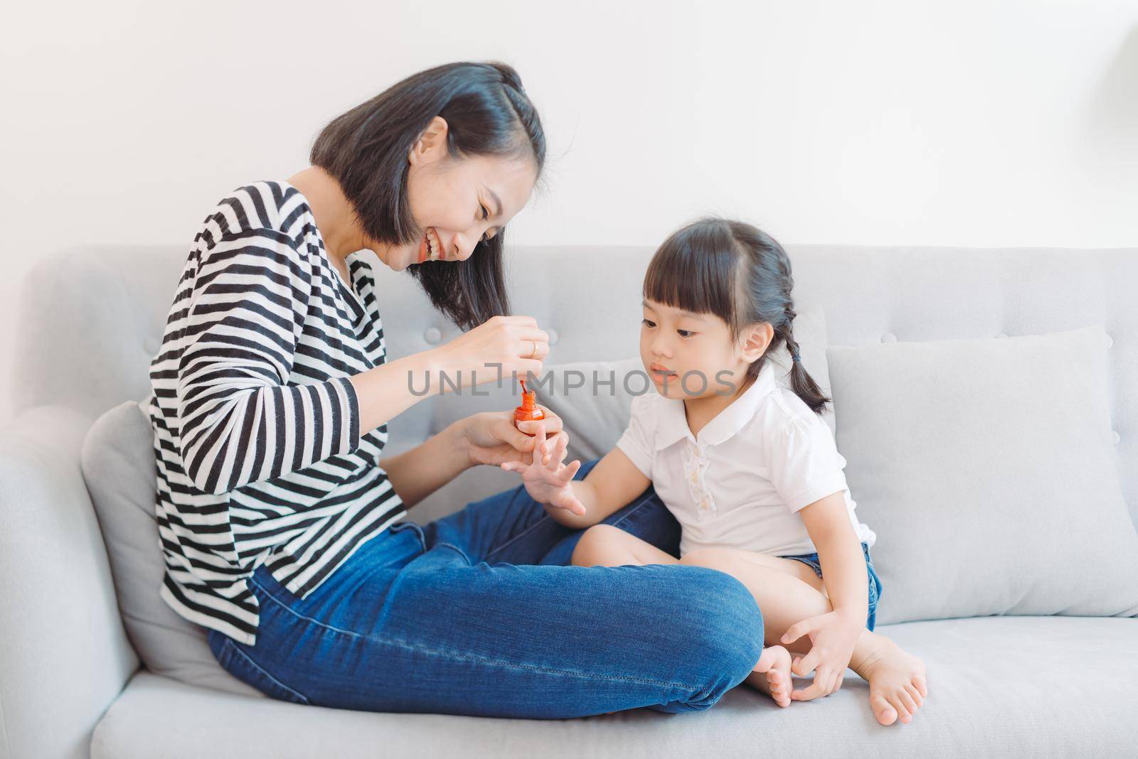 Mother and daughter having fun painting fingernails, family time concept