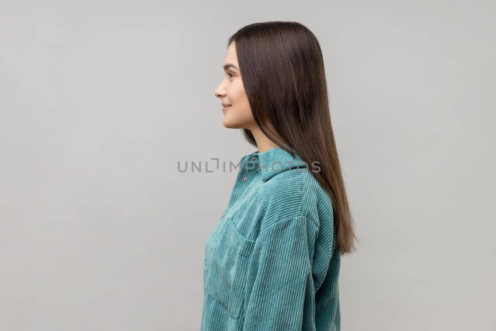 Side view of happy successful young woman standing looking at camera with charming and toothy smile, by Khosro1