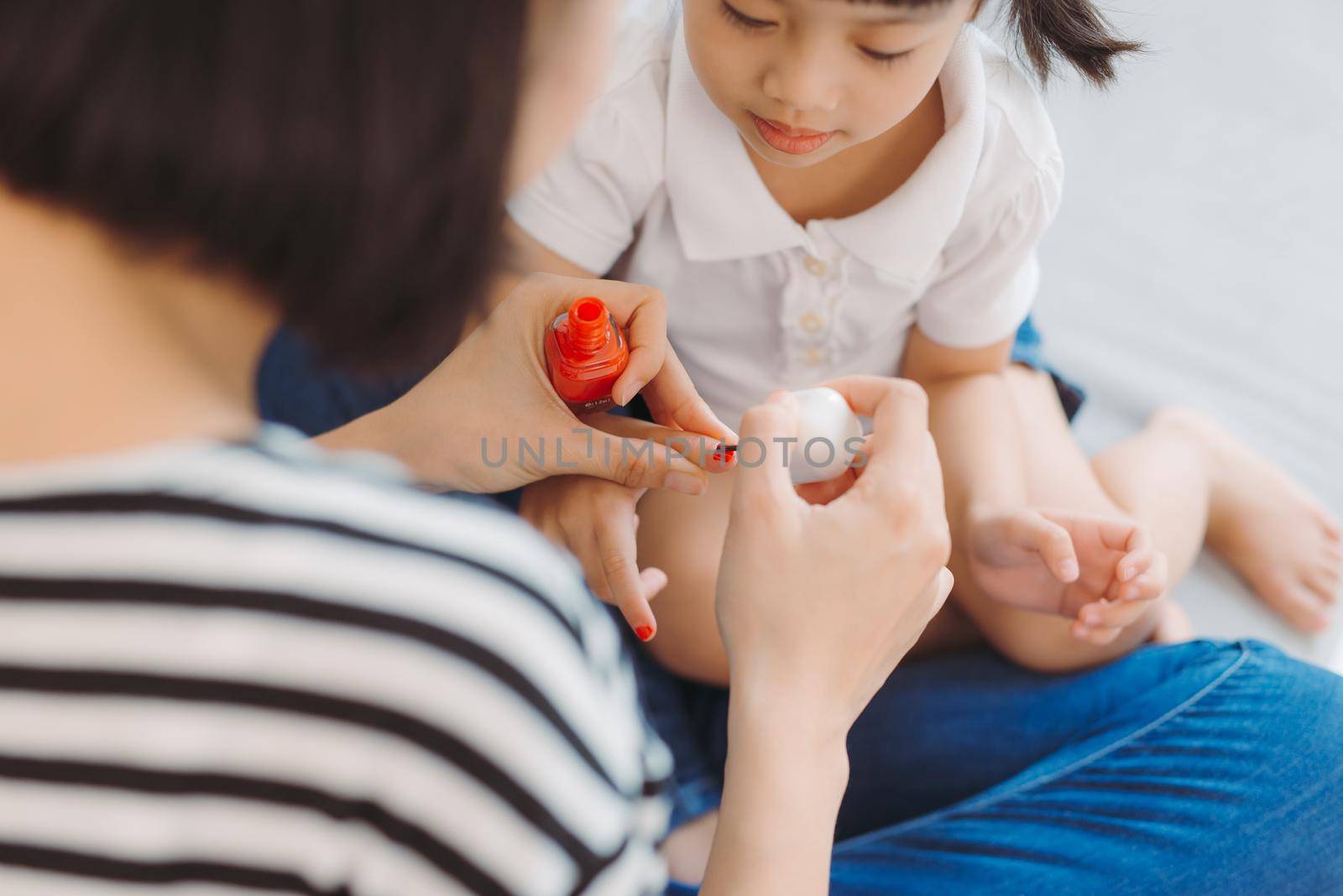 Mother and daughter painting their finger nails with polish by makidotvn