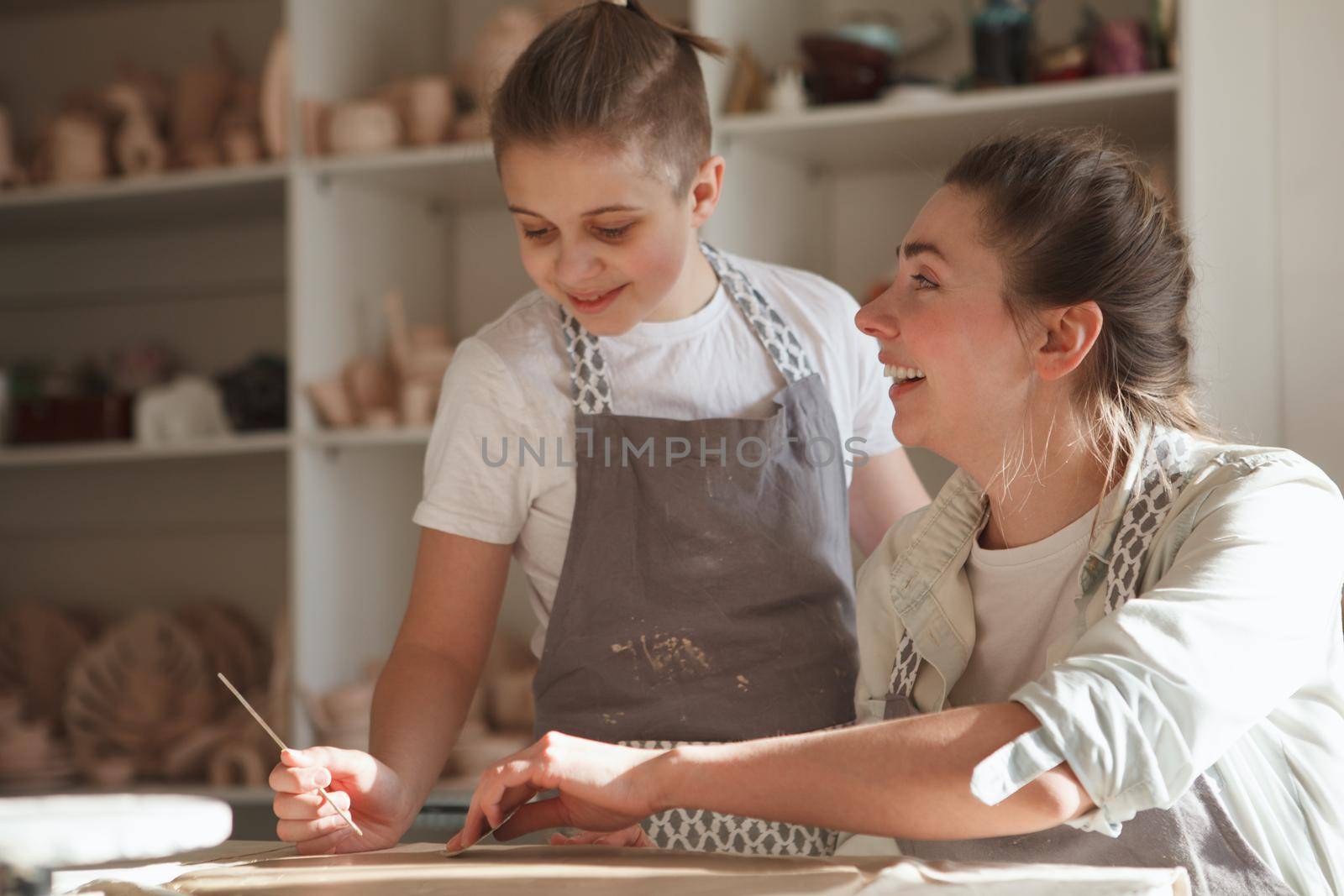 Cheerful woman laughing while learning pottery with her son at art studio