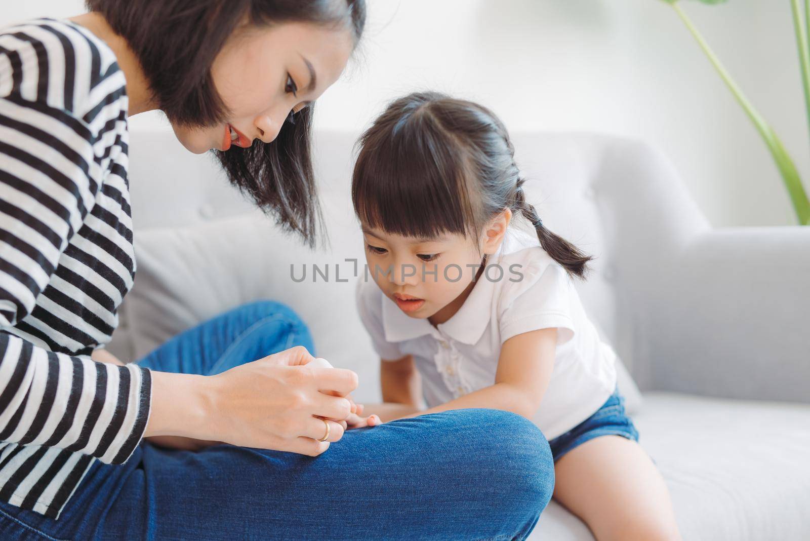 Little daughter with mother making pedicure at home by makidotvn