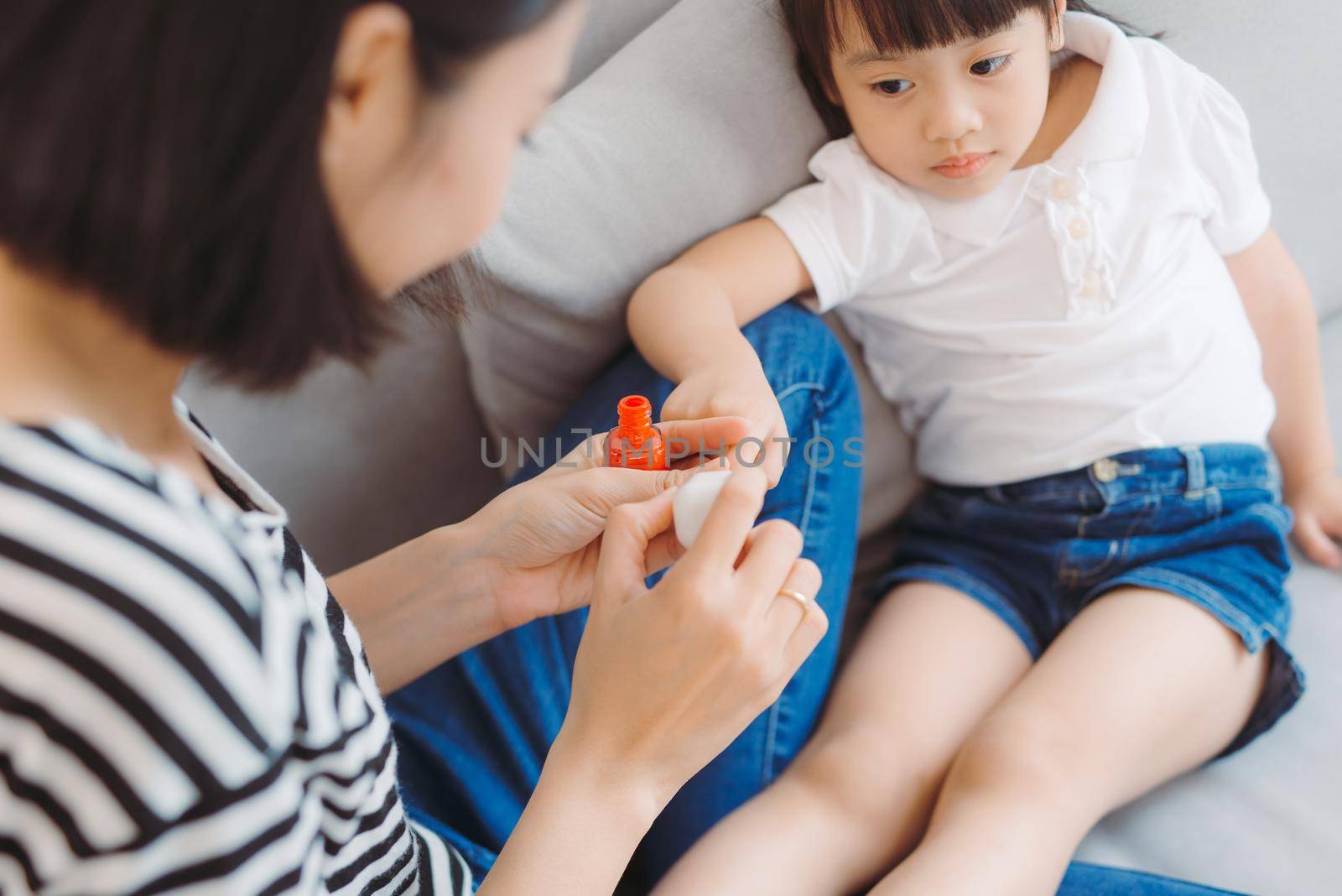 Little daughter with mother making pedicure at home