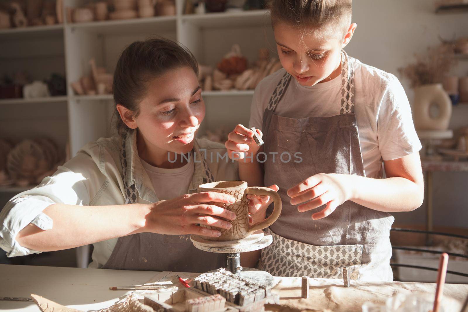 Young boy and his mother decorating handmade kitchenware at art workshop
