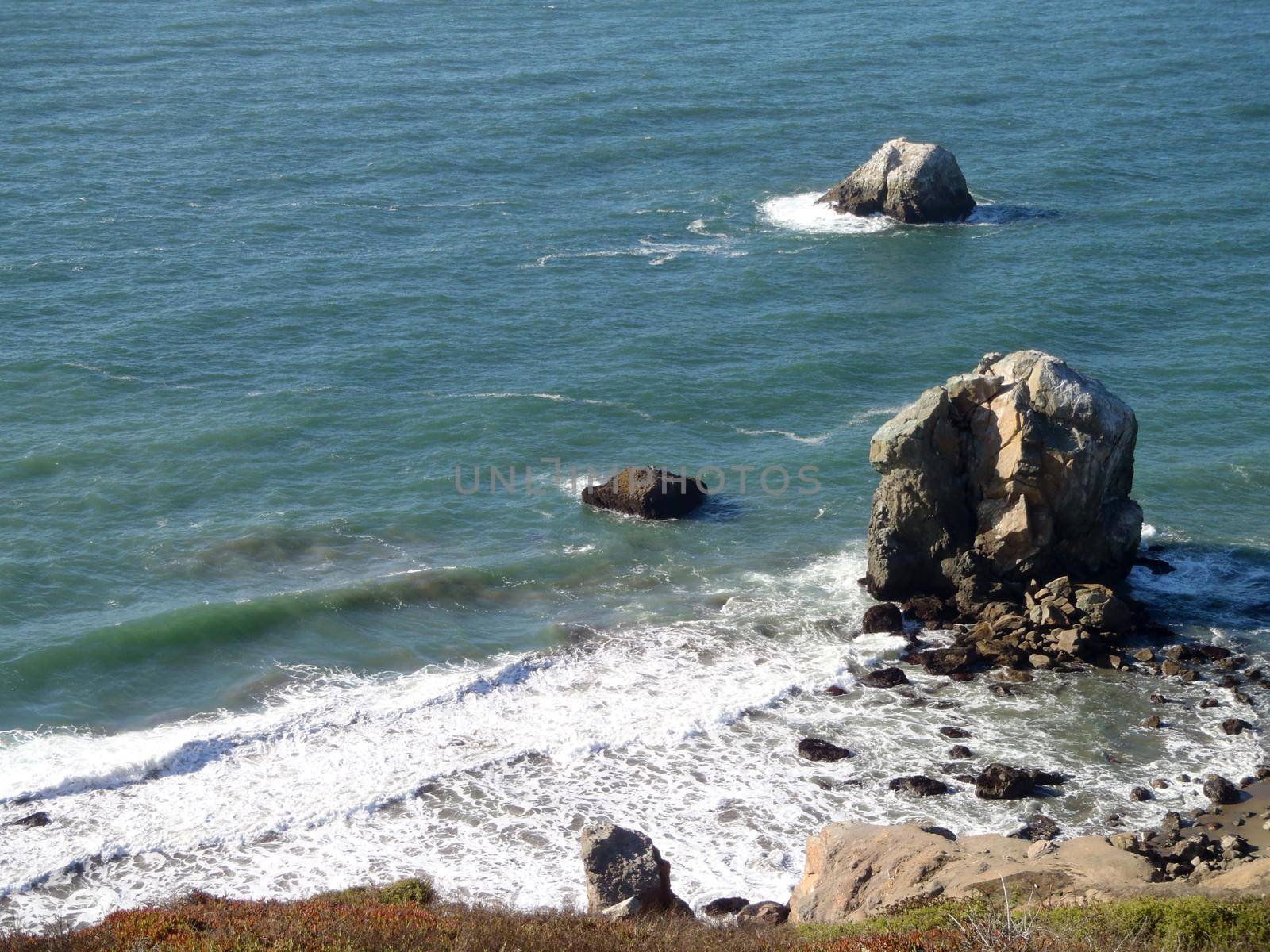 Waves roll toward large rocks and shore on the coast of Marin in California.