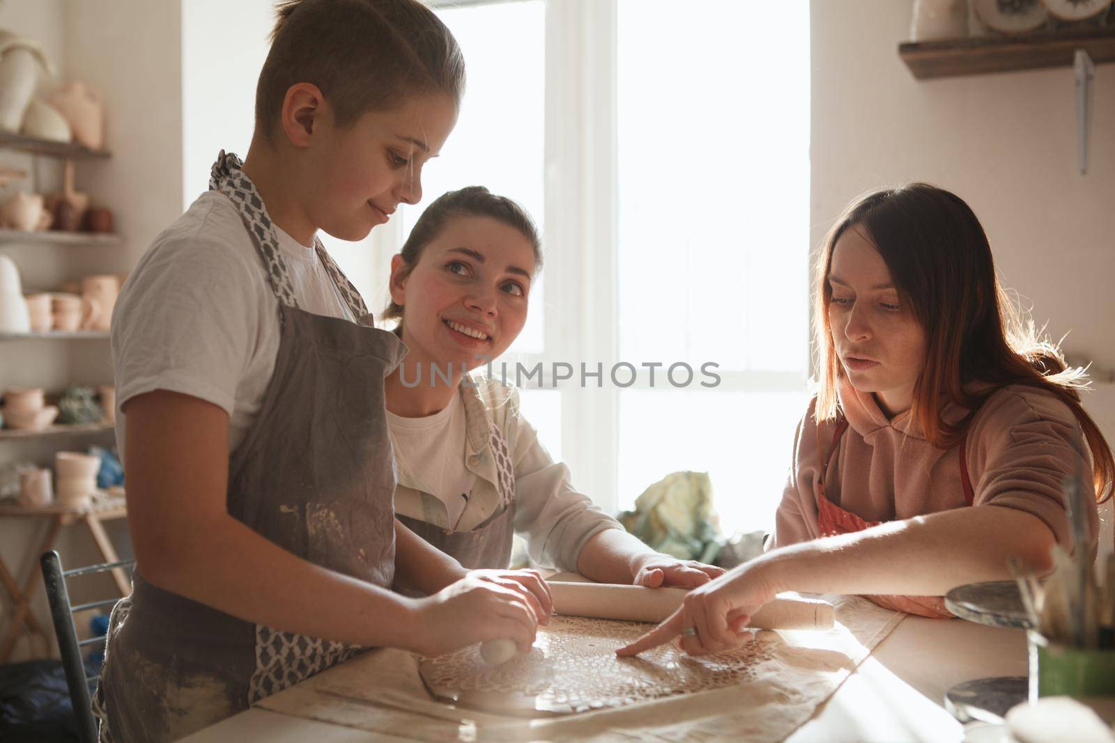 Young boy making ceramics at pottery class with his mother and professional potter