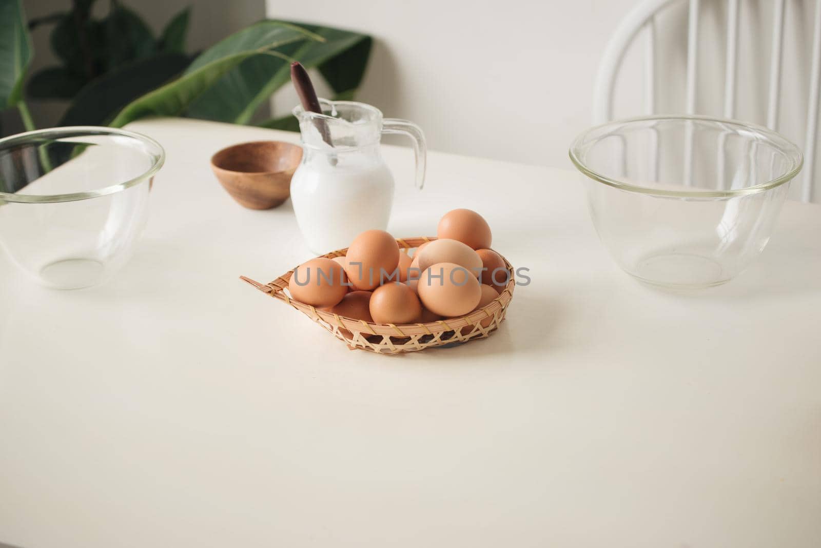 brown eggs in a wicker basket on a light wooden table and a side view