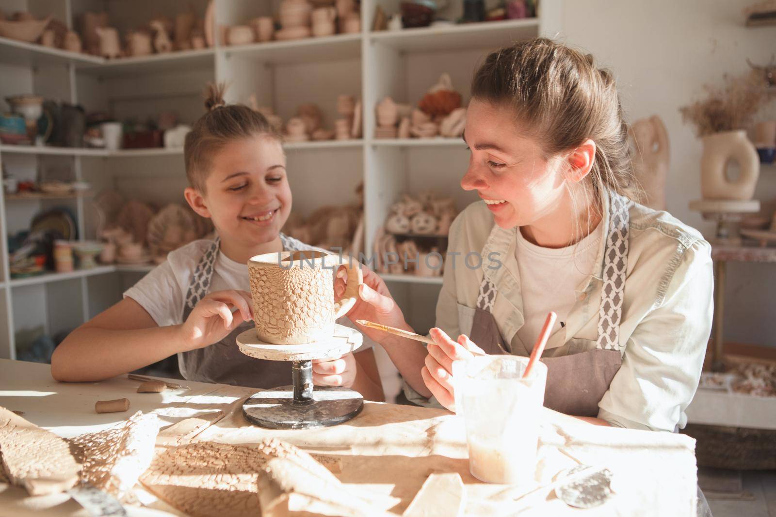 Young boy laughing with his mom while making tableware together at pottery studio