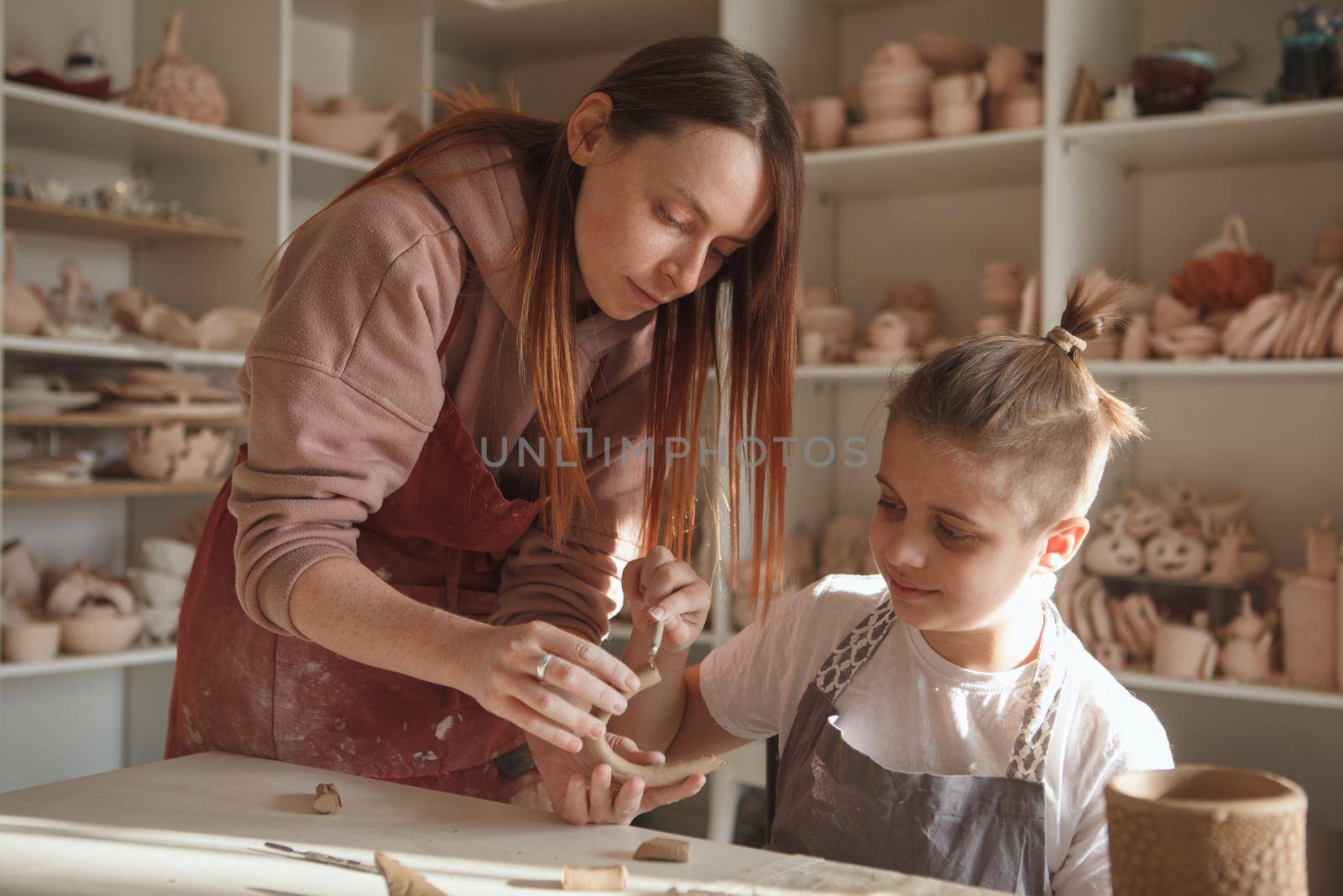 Female potter teaching art workshop for a young boy