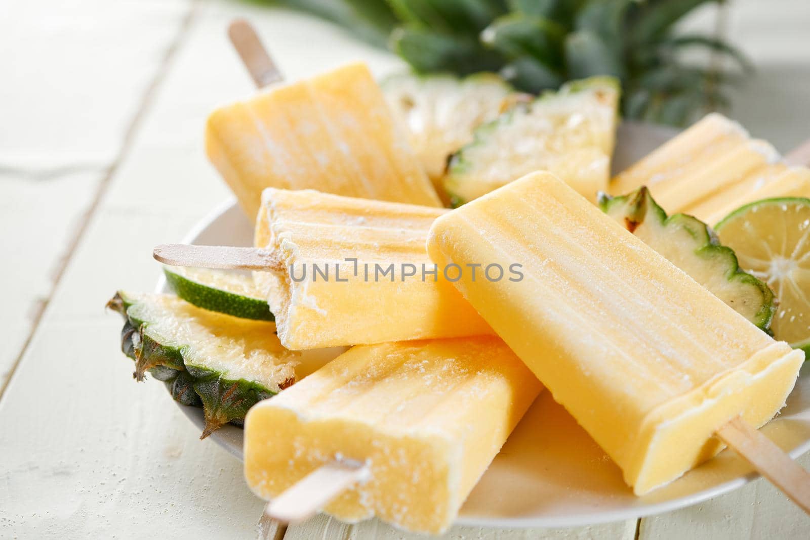 Pineapple coconut popsicles in a cluster on wooden white background