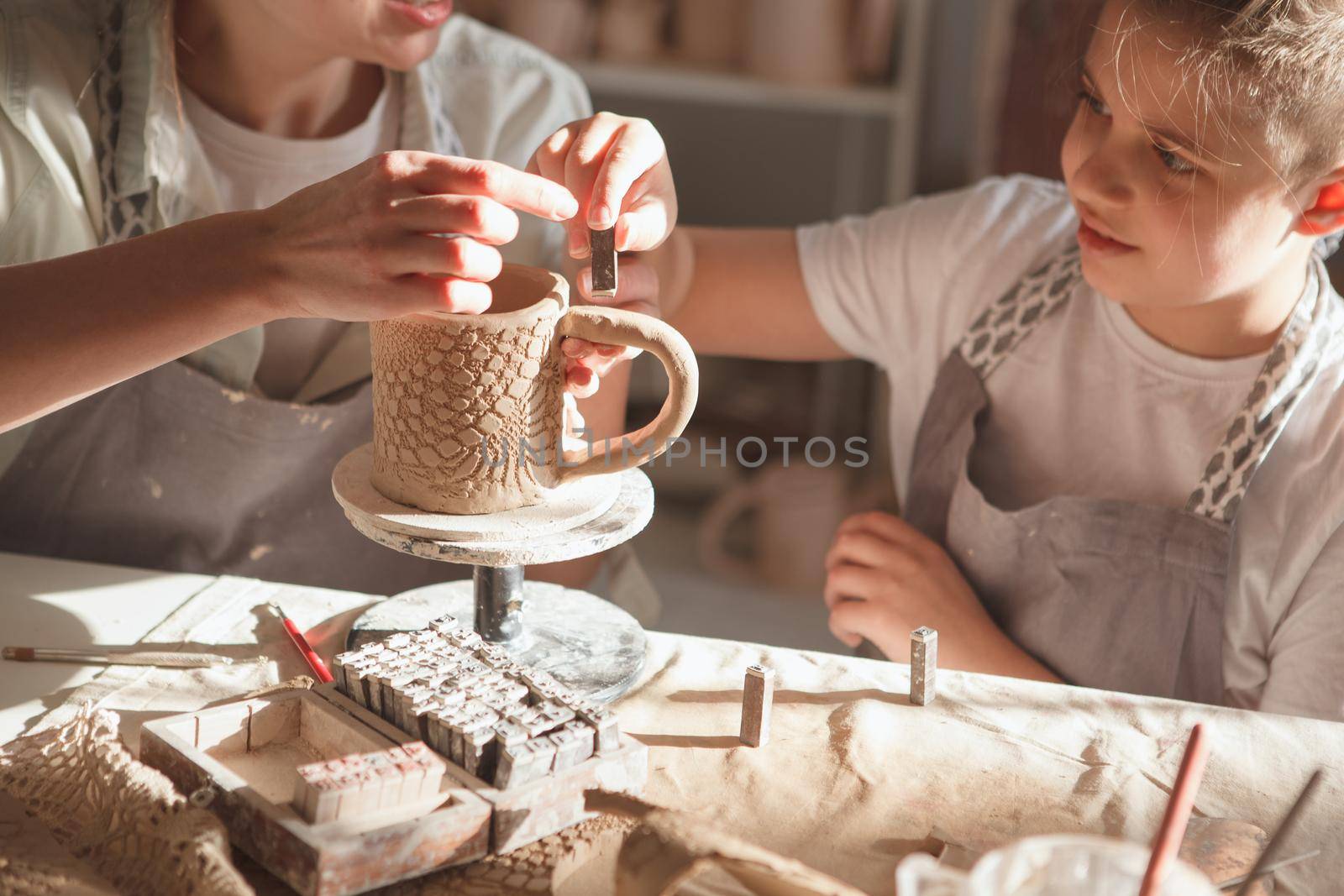 Cropped shot of a mom and son decorating handmade ceramic mug