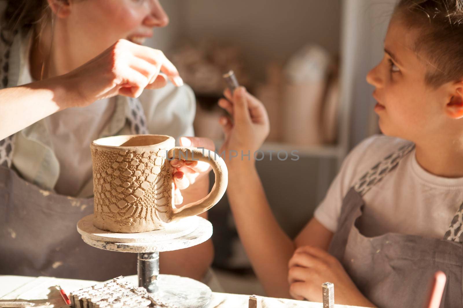 Young boy and his mother decorating handmade ceramic cup