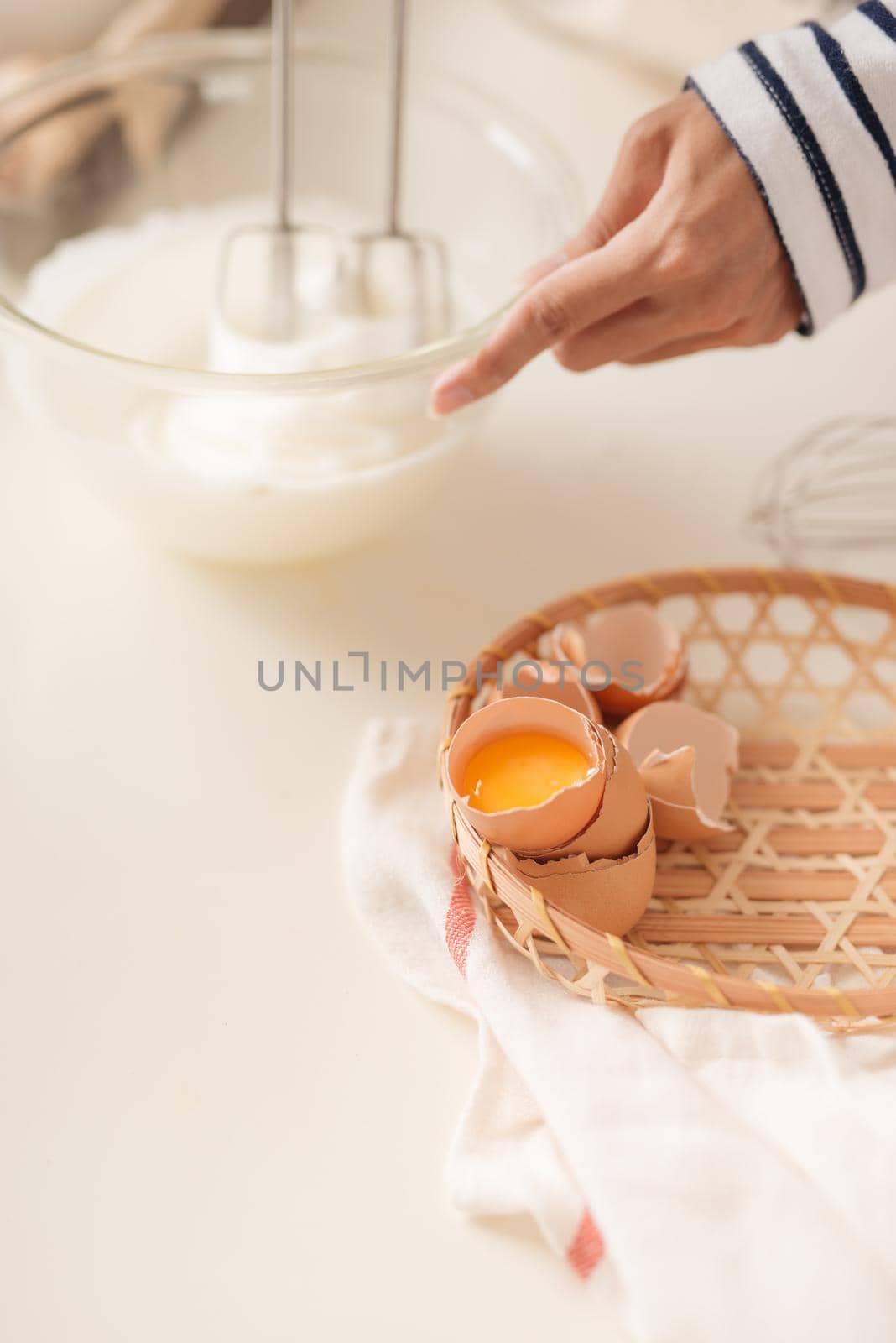 Mixing white egg cream in bowl with motor mixer, baking cake 