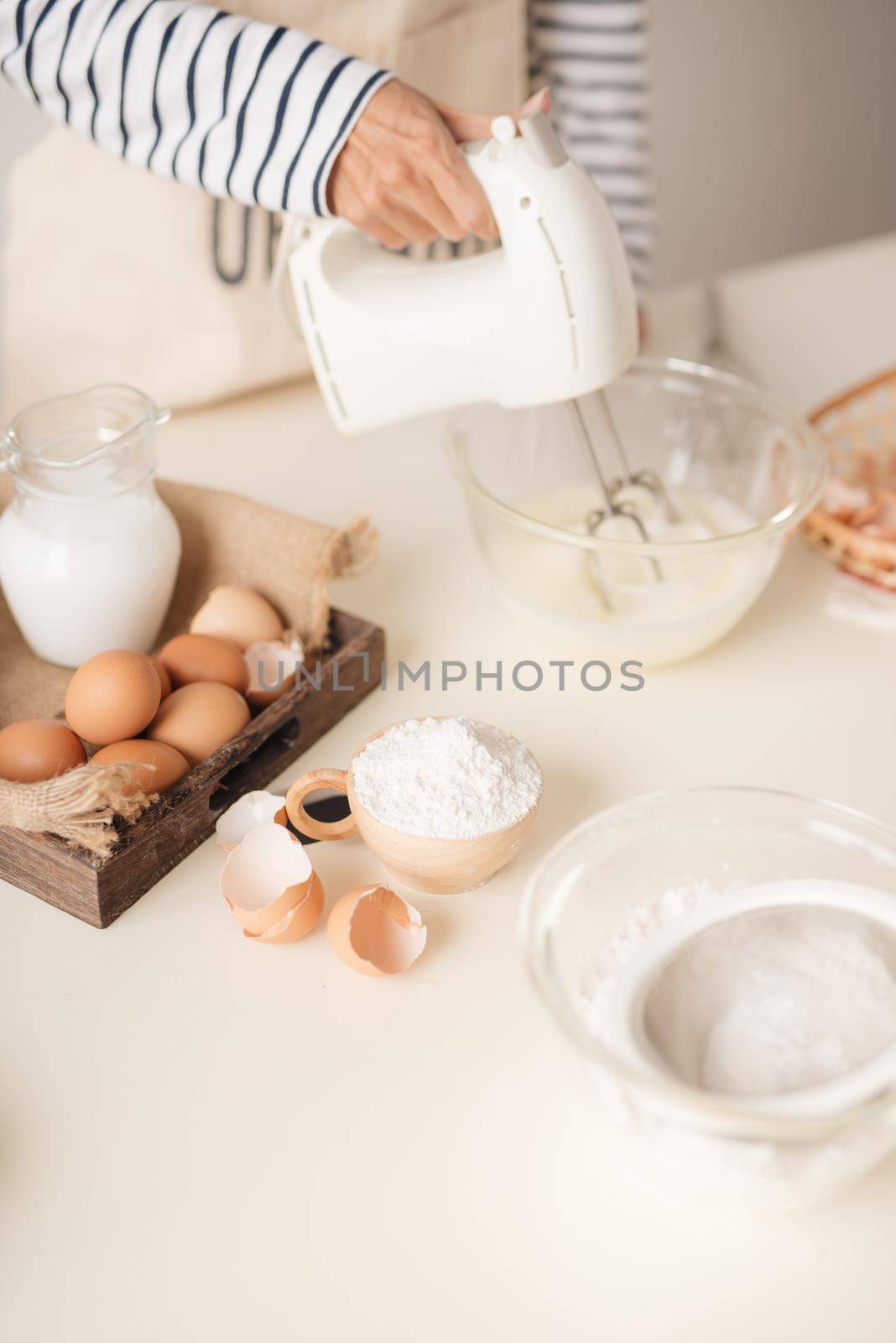Male hands beating egg whites cream with mixer in the bowl