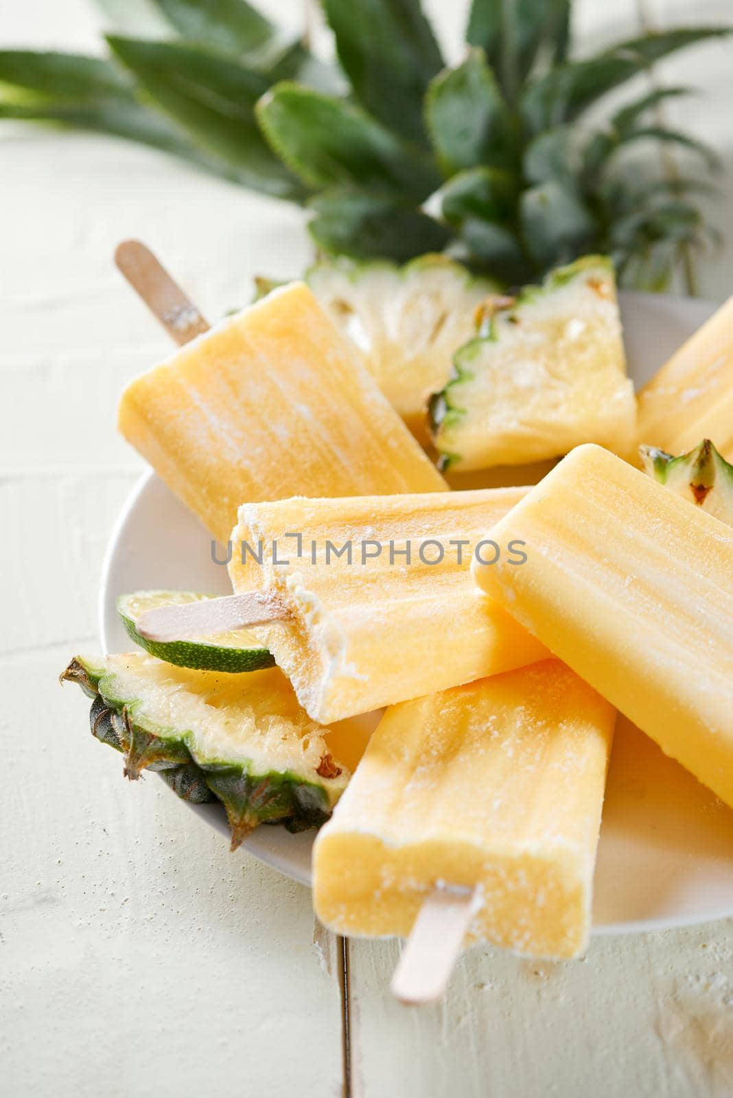 Pineapple coconut popsicles in a cluster on wooden white background