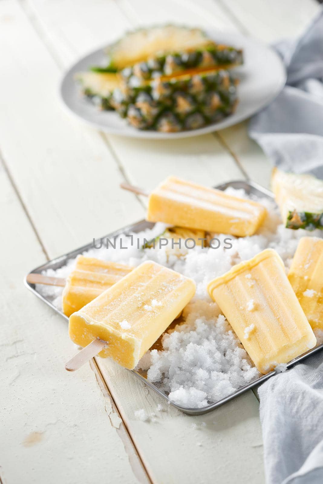 Yellow fruit popsicles on a plate. Top view over a white wood background. by makidotvn