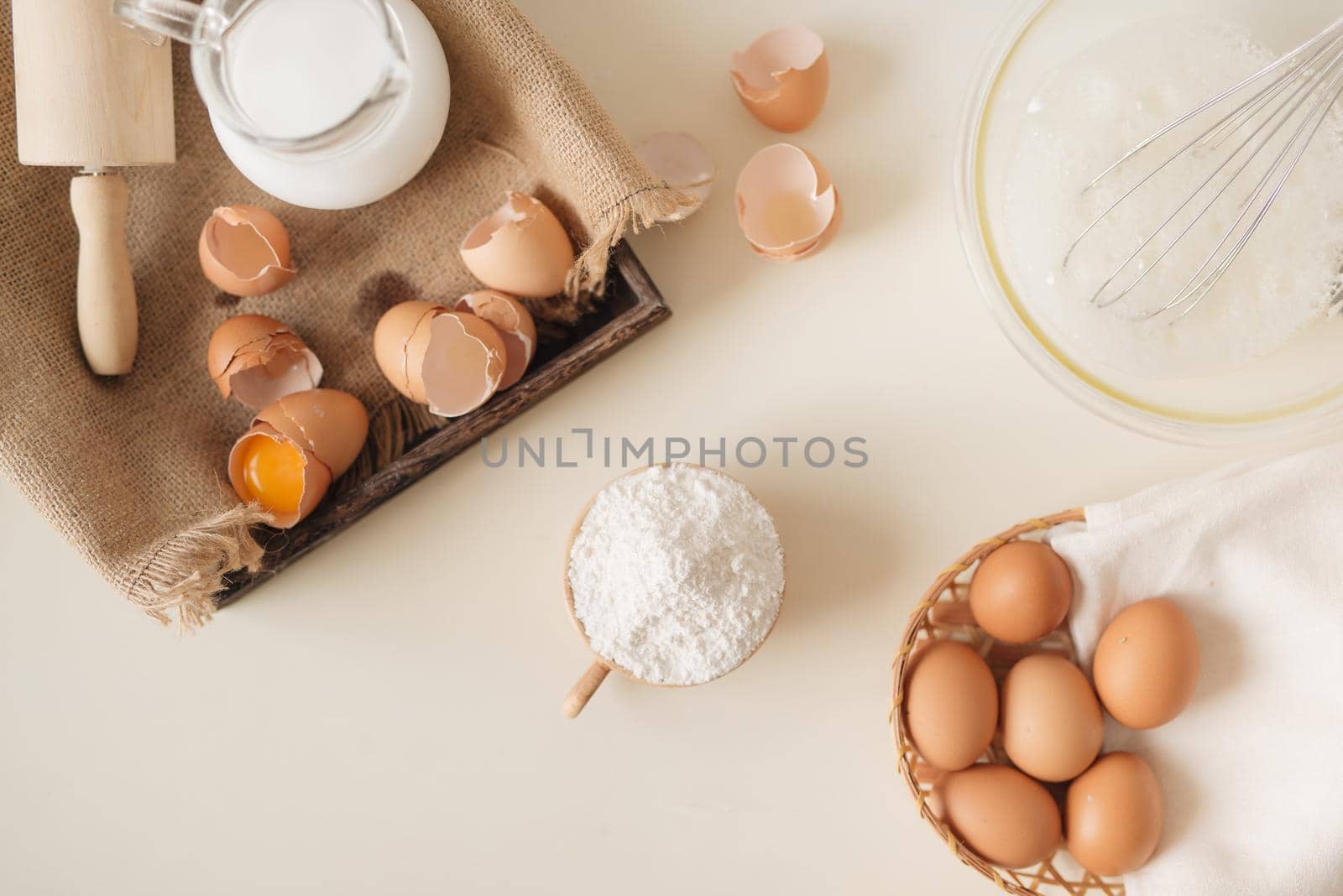 Young man's hands whisk eggs with sugar to bake fruit cake. Male cooking dough for pie on white table