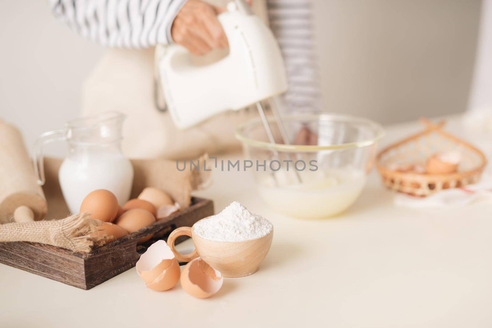 Male hands beating egg whites cream with mixer in the bowl