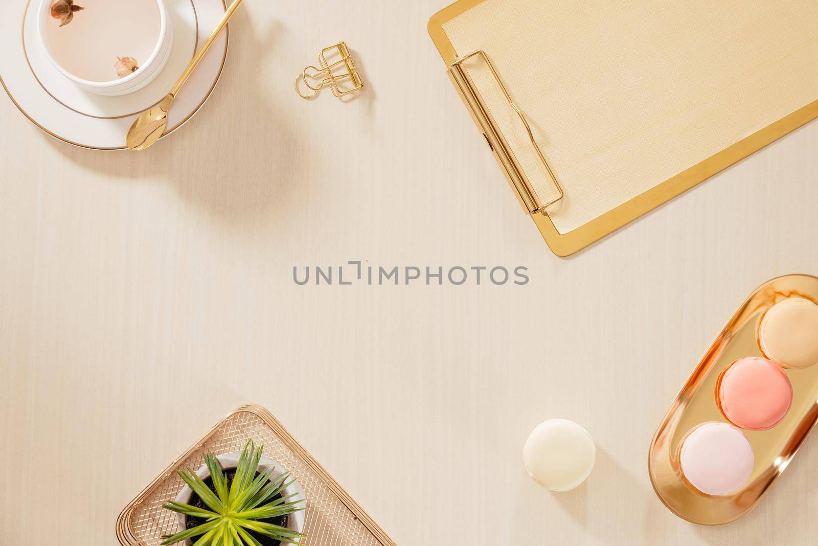 Women's home office workspace with clipboard, macaroons, pen, coffee mug on pastel background. Flat lay, top view lifestyle concept.