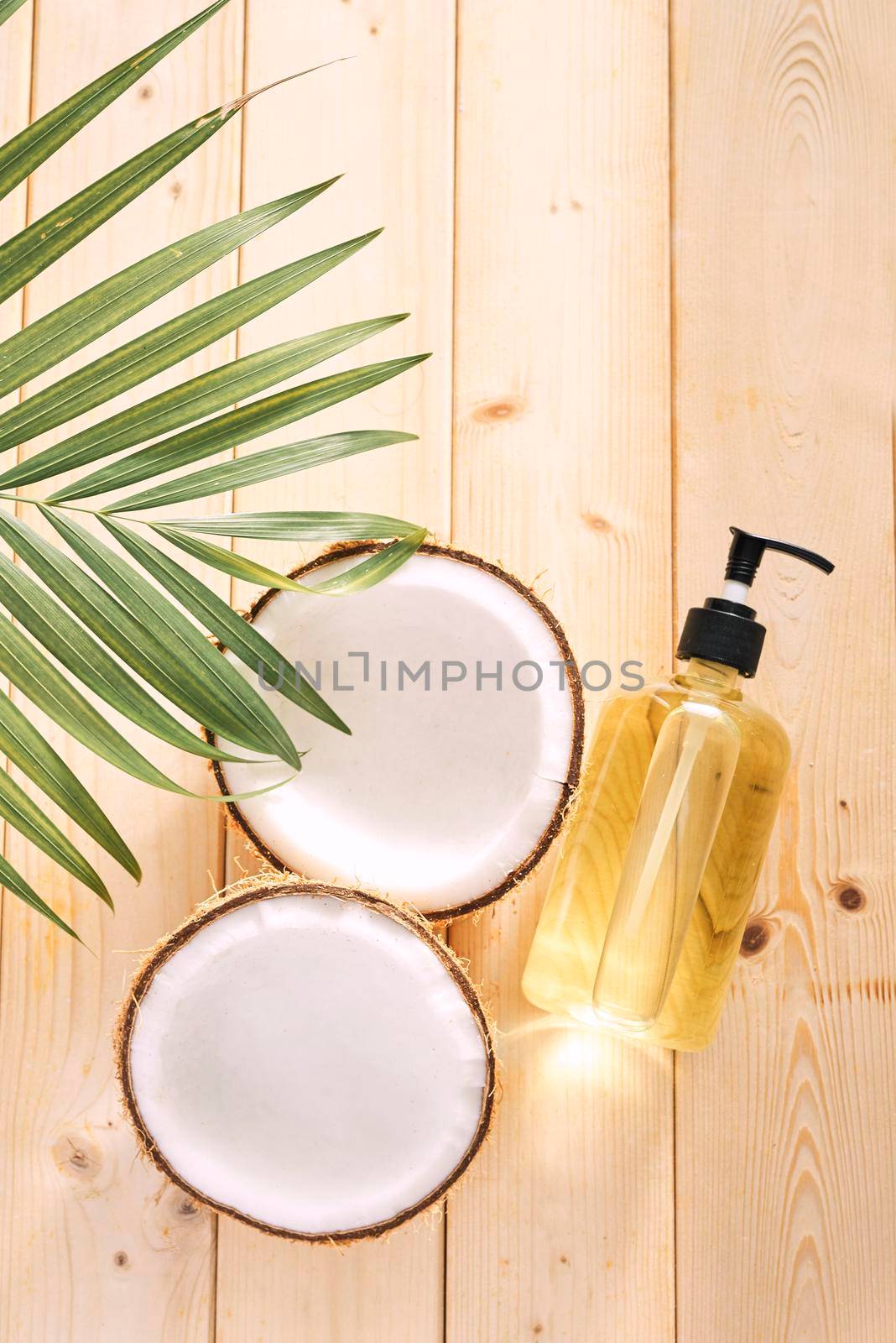 Cracked coconut and a bottle of oil on the table - spa, skincare, haircare and relaxation concept  by makidotvn