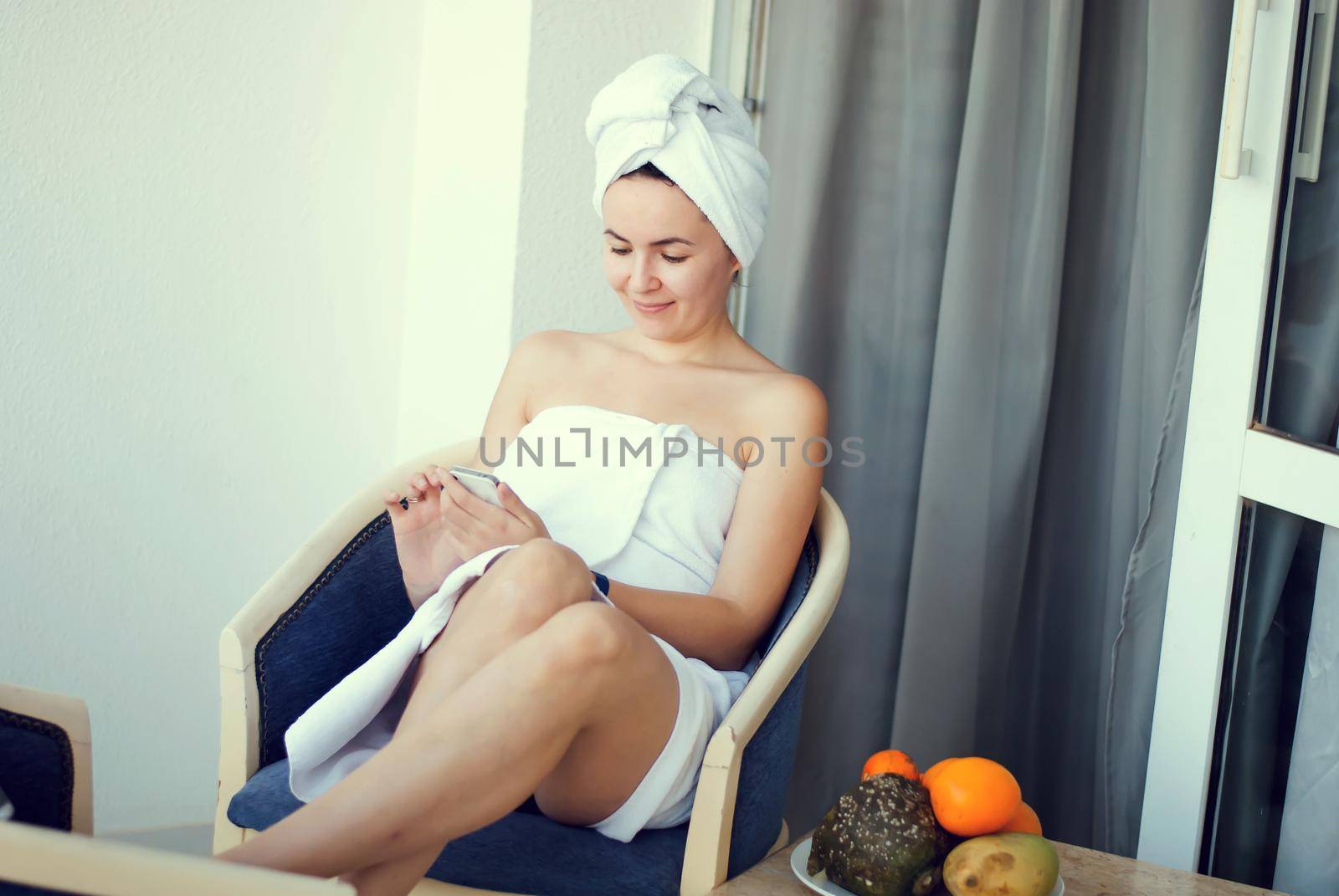 young smiling woman in the hotel talking mobile phone wearing white shower towel