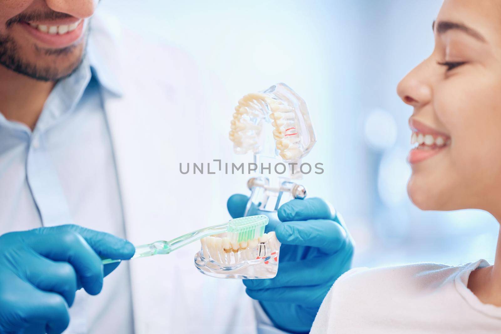 The best way to keep clean. a dentist demonstrating the best way to brush teeth to a patient. by YuriArcurs