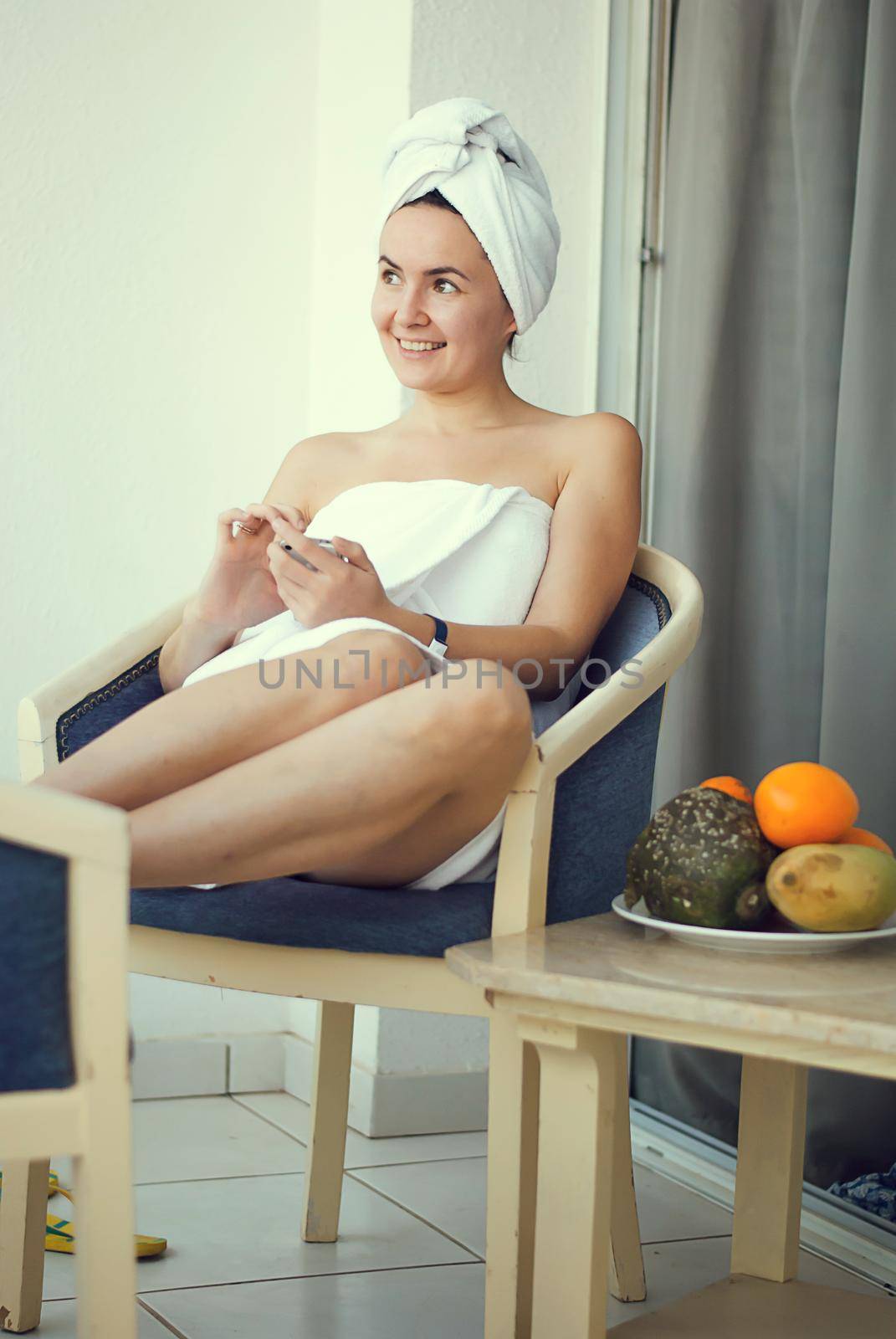 young smiling woman in the hotel talking mobile phone wearing white shower towel