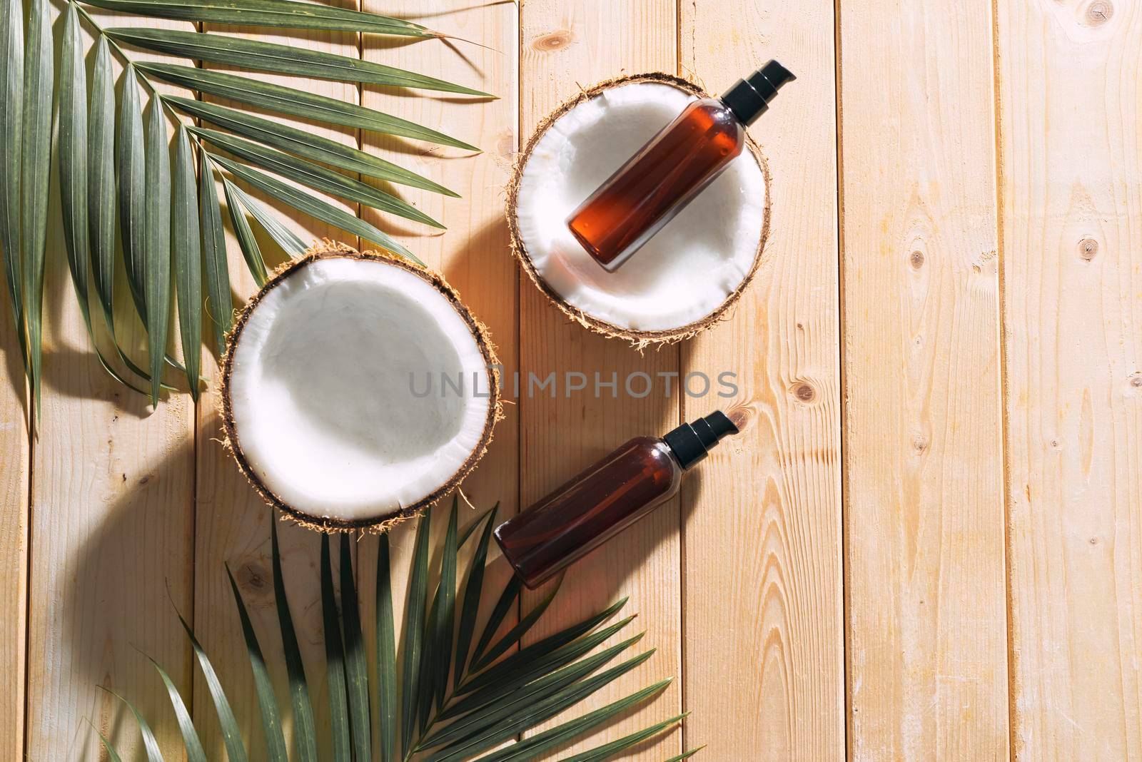 Tropical leaf, care cosmetics and coconut on a wooden table. Top view. Means for hair, body, skin. flatlay by makidotvn