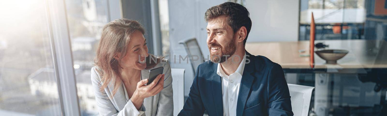 Smiling businessmen at work talk phone and discussing their business by Yaroslav_astakhov