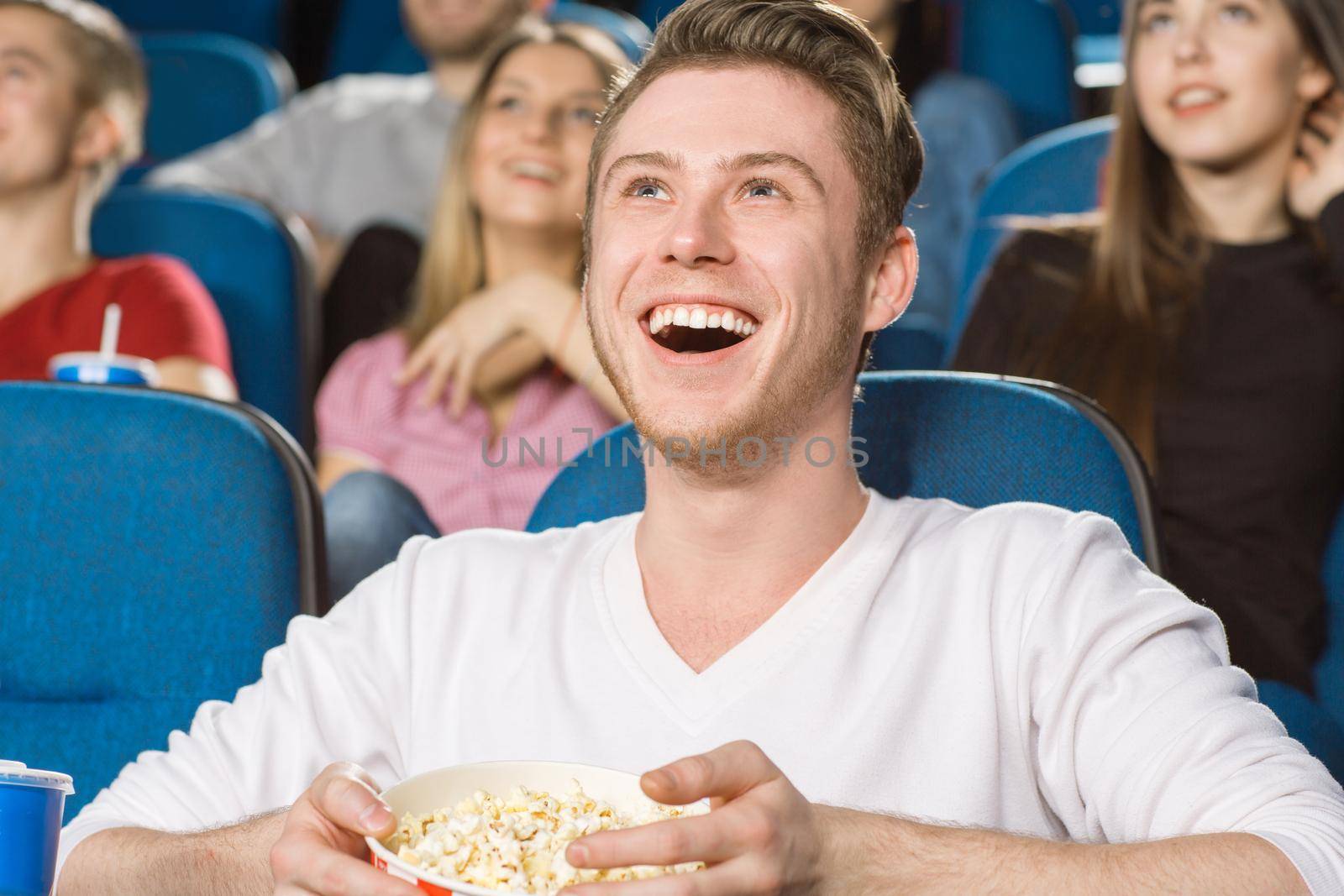 In love with comedies. Portrait of a young excited man laughing while watching a comedy movie at the local cinema