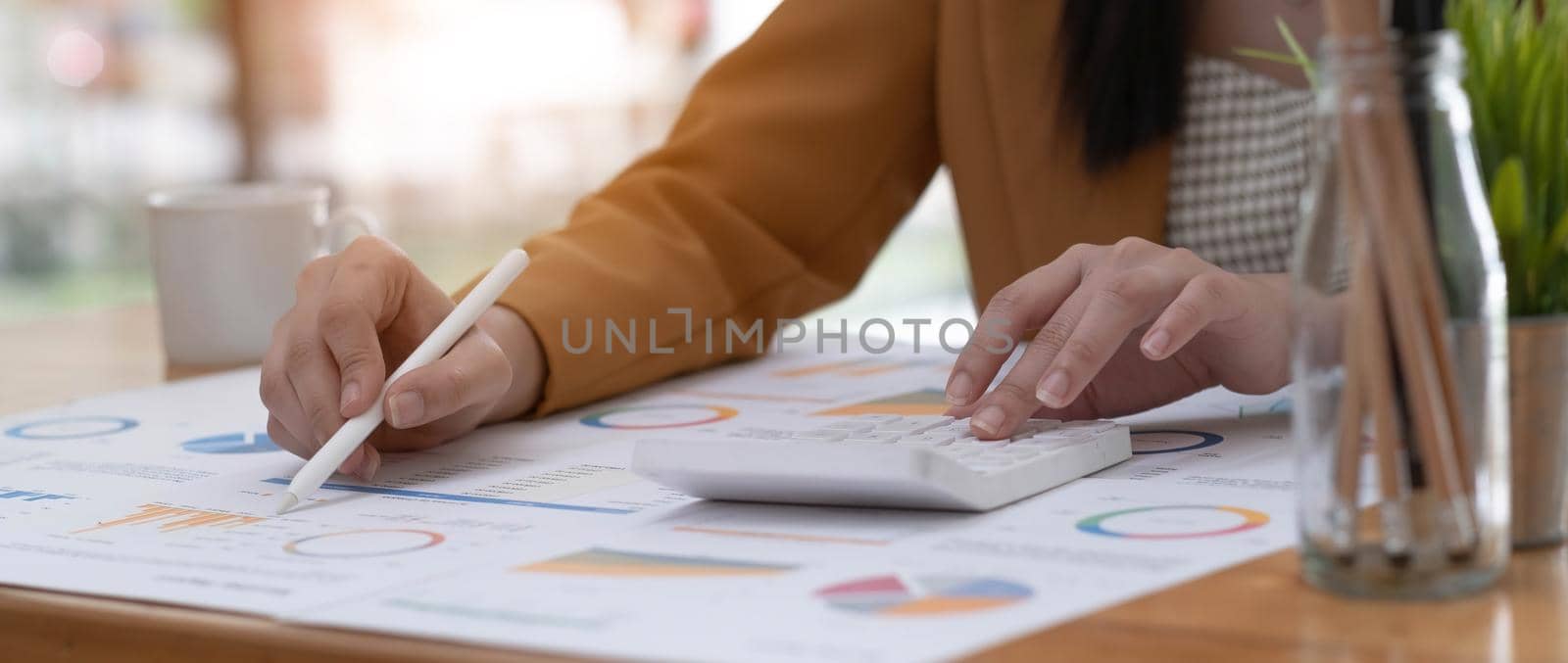 Business woman using calculator to calculate financial report, working at office with laptop computer on table. Asian female accountant or banker making calculations. finances and economy concept.