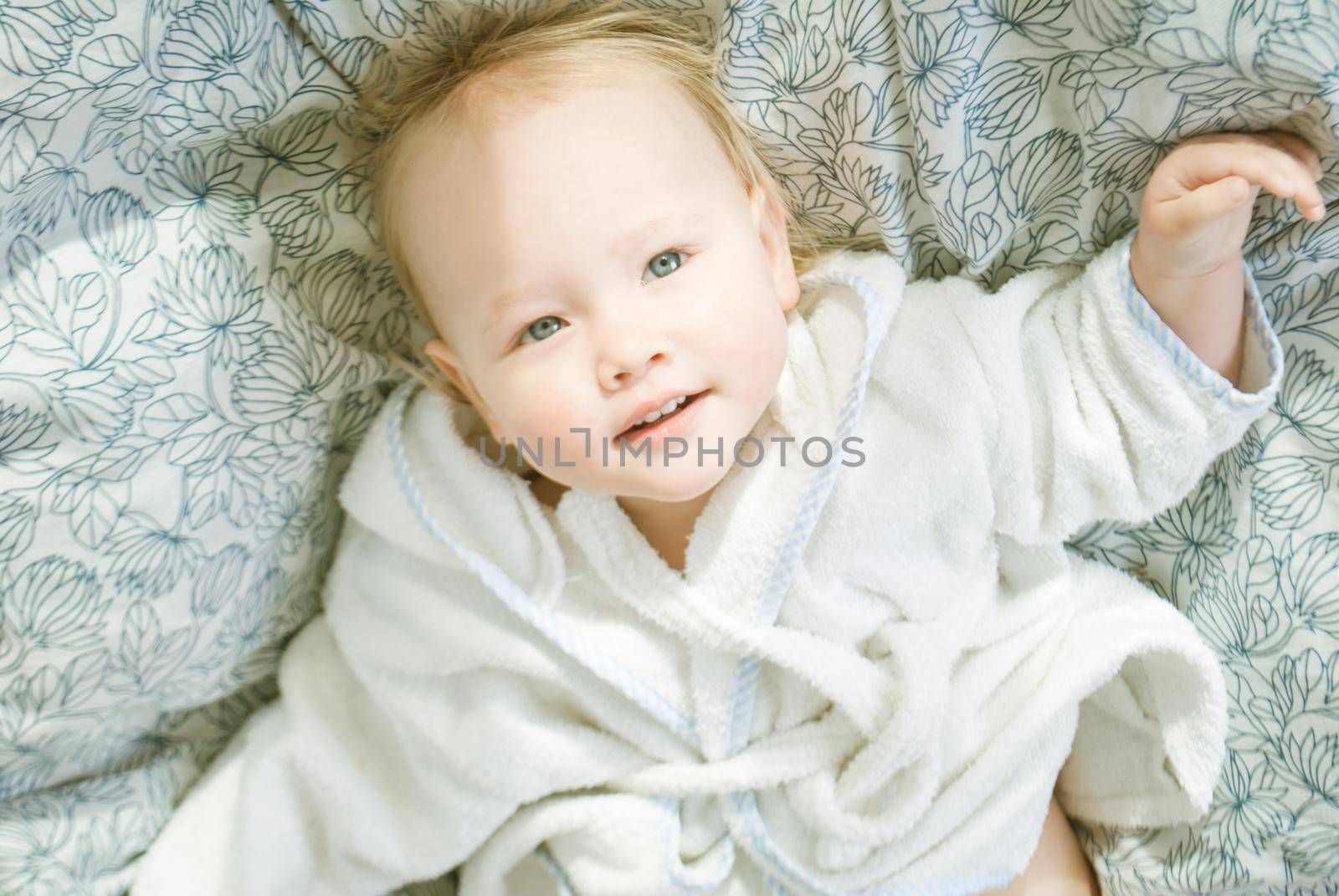 cute babygirl in parents bed in bathrobe relaxing and smilling