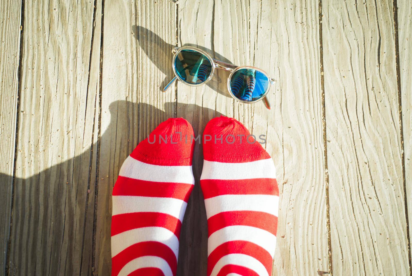 Concept of summer vacation with red striped socks and sunglesses on sea pier