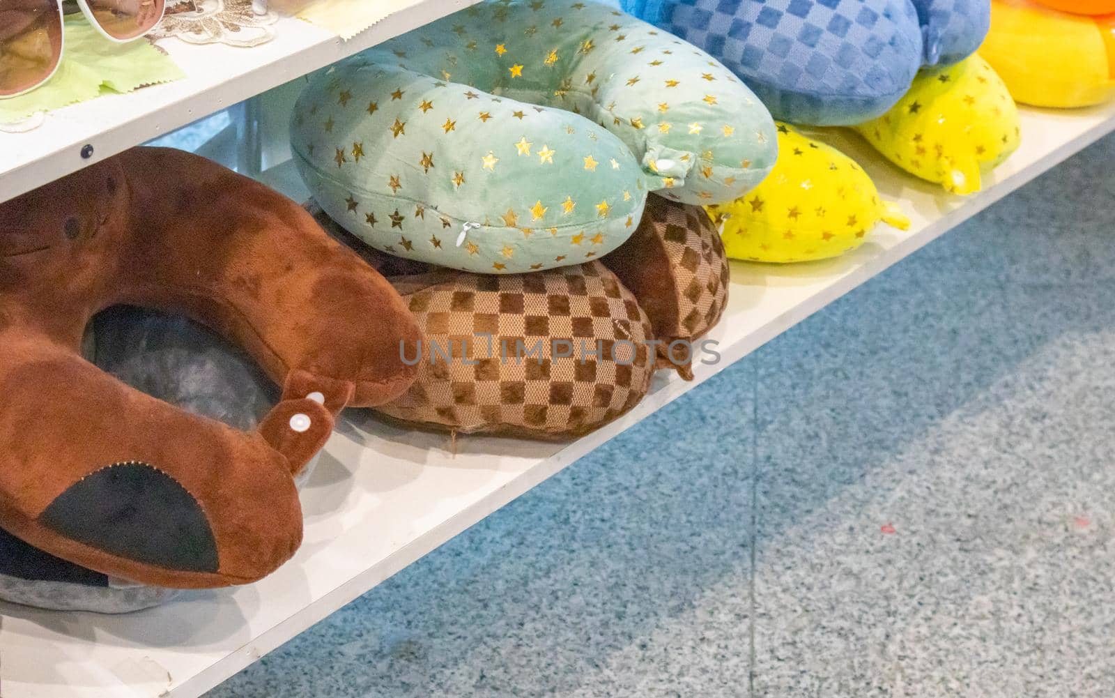 A lot of colorful inflatable and soft pillows for the convenience of the neck during travel, lie on the counter of the store, the concept of selling goods on the road by claire_lucia