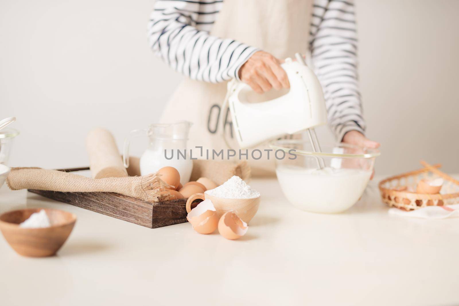 Mixing white egg cream in bowl with motor mixer, baking cake 