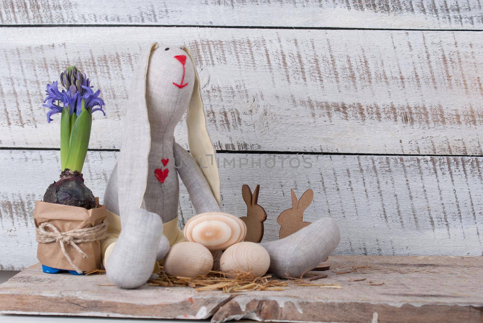 Easter decoration with wooden eggs, rabitt and flowers on wooden background