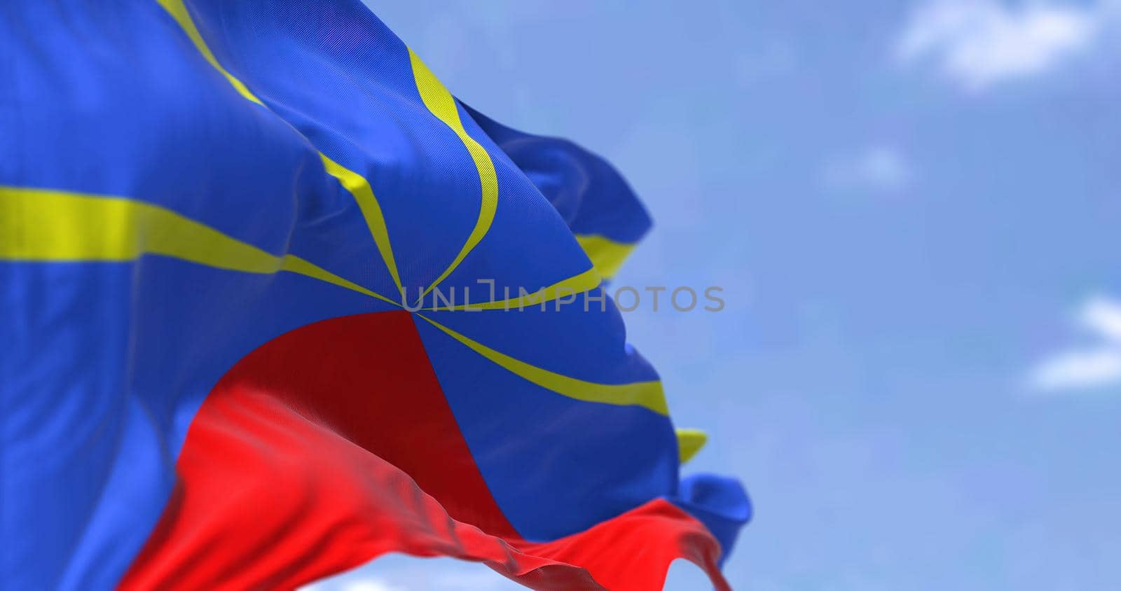 The flag of Reunion waving in the wind on a clear day. Reunion is an island in the Indian Ocean that is an overseas department and region of France