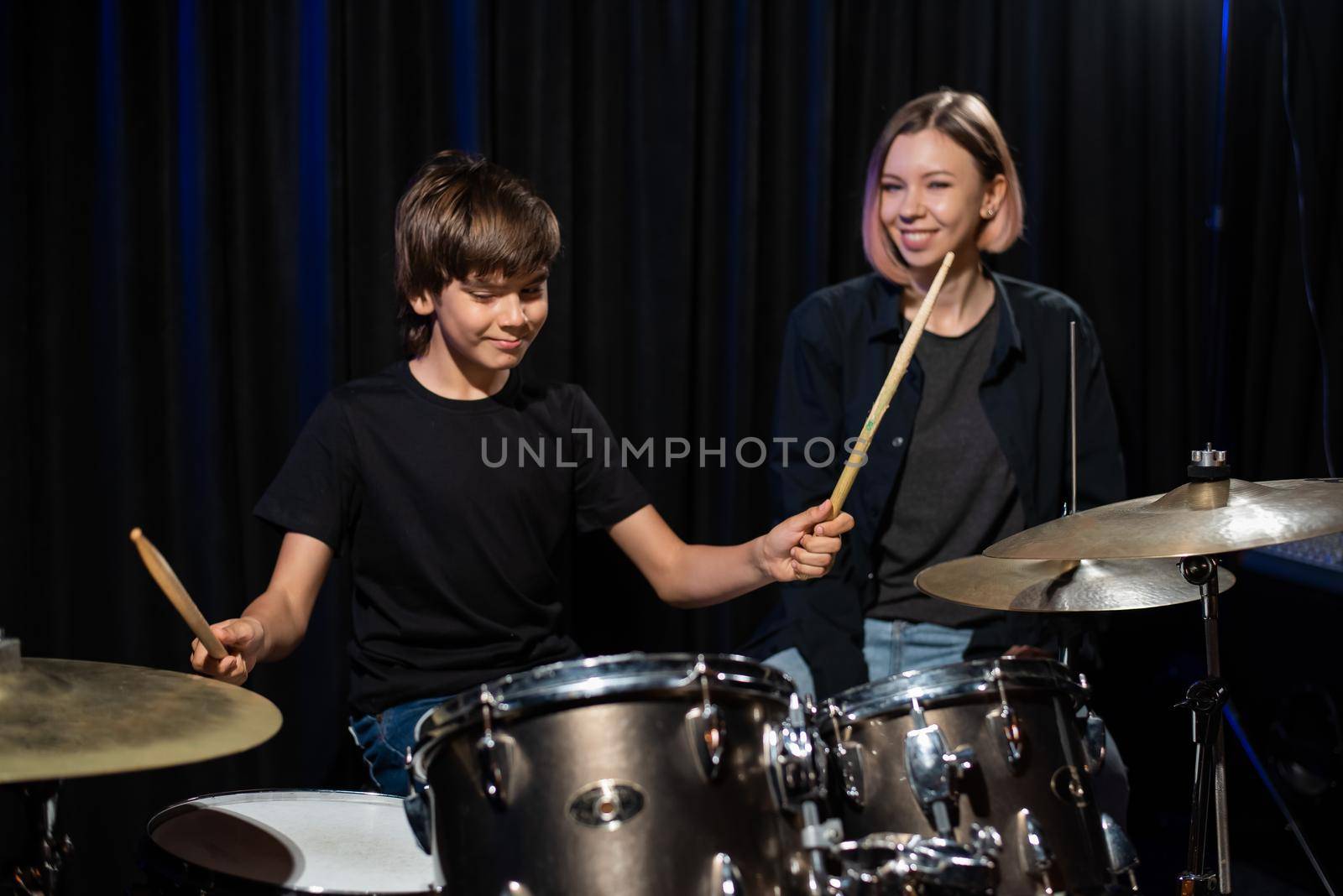 Young woman teaching boy to play drums