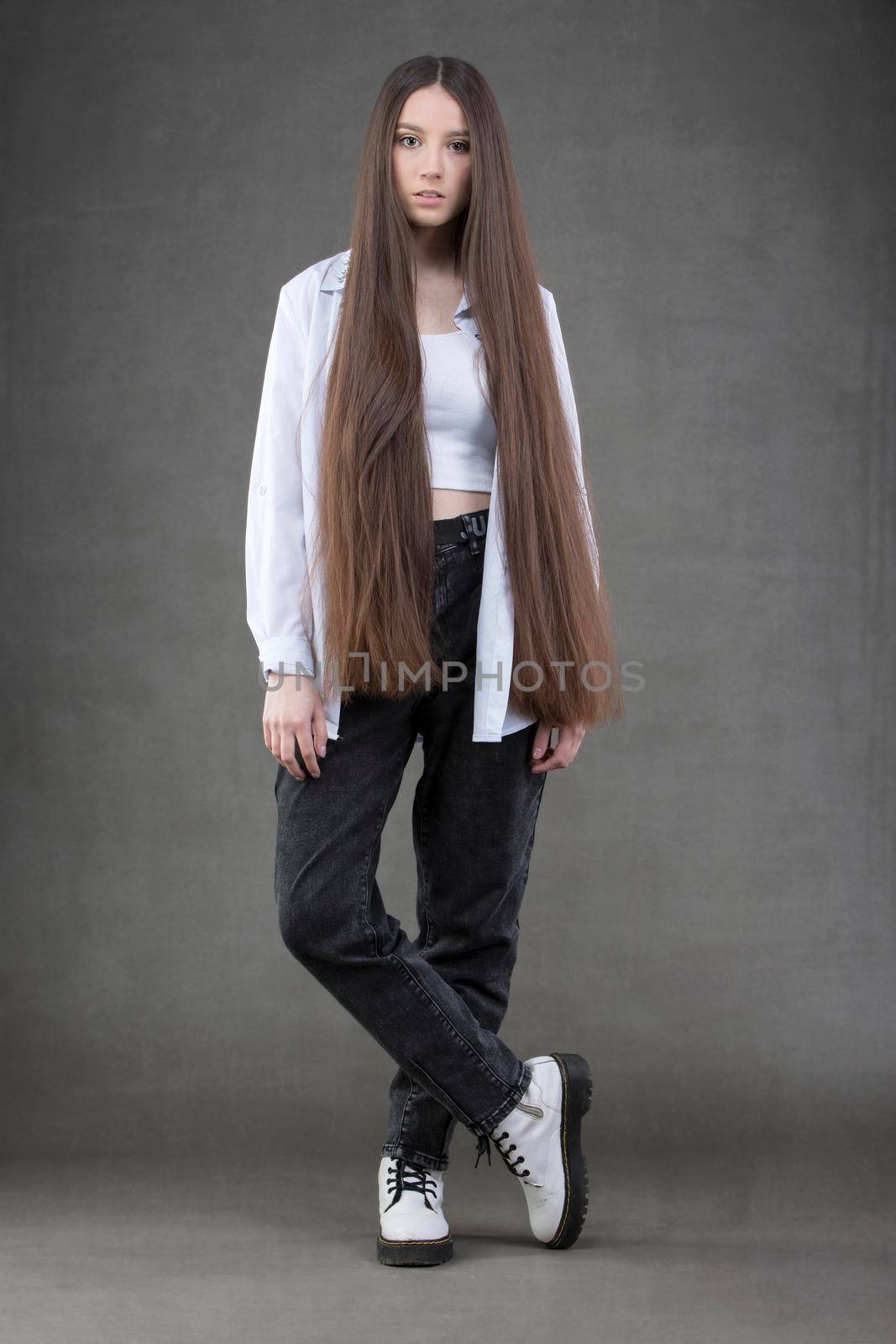 Beautiful brunette girl with very long hair on a gray background.