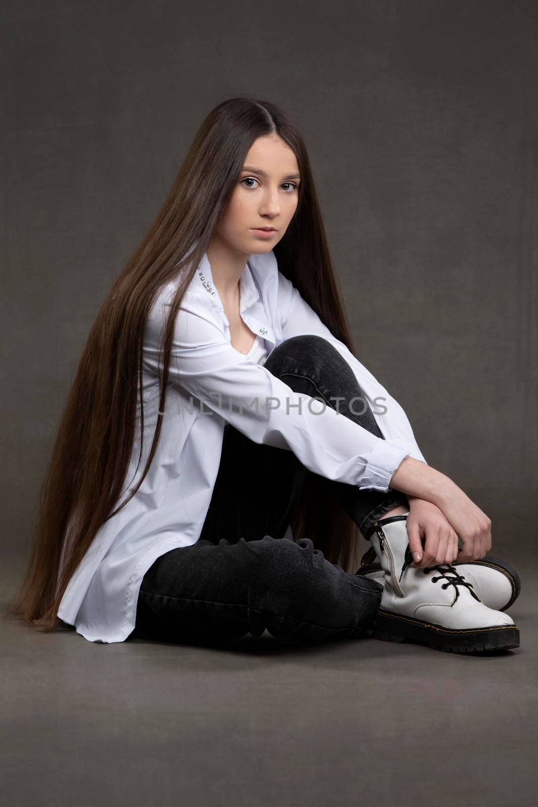 Beautiful brunette girl with very long hair on a gray background.