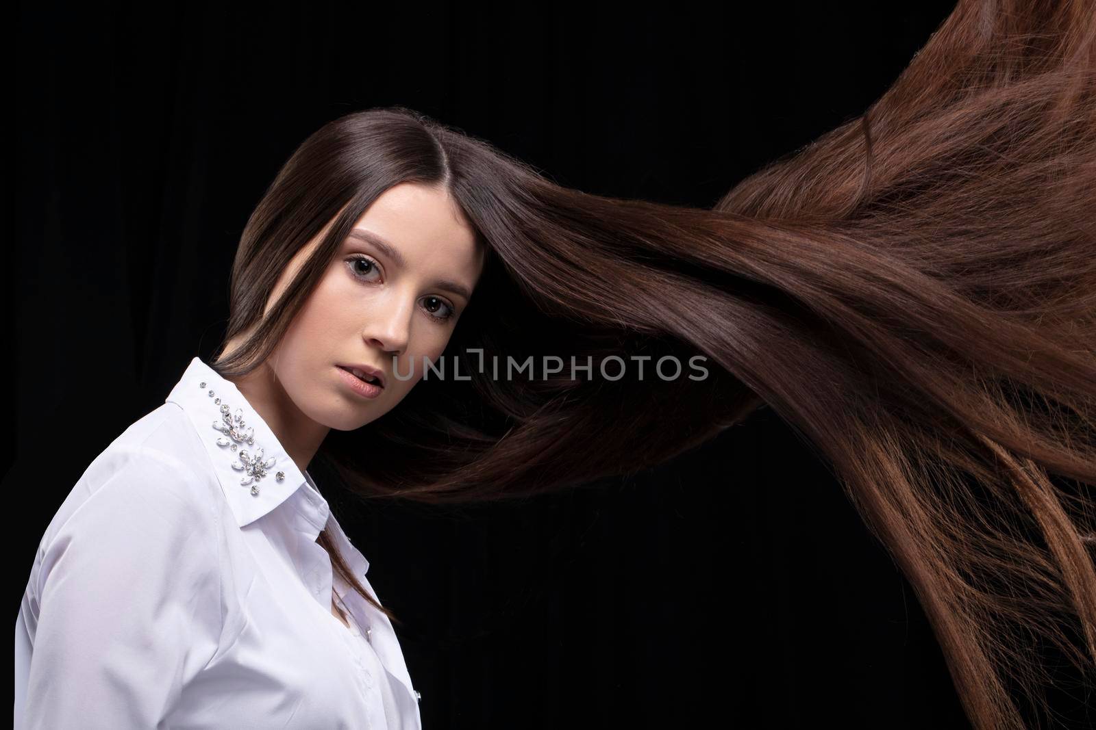 Beautiful brunette with long flying hair on a dark background.